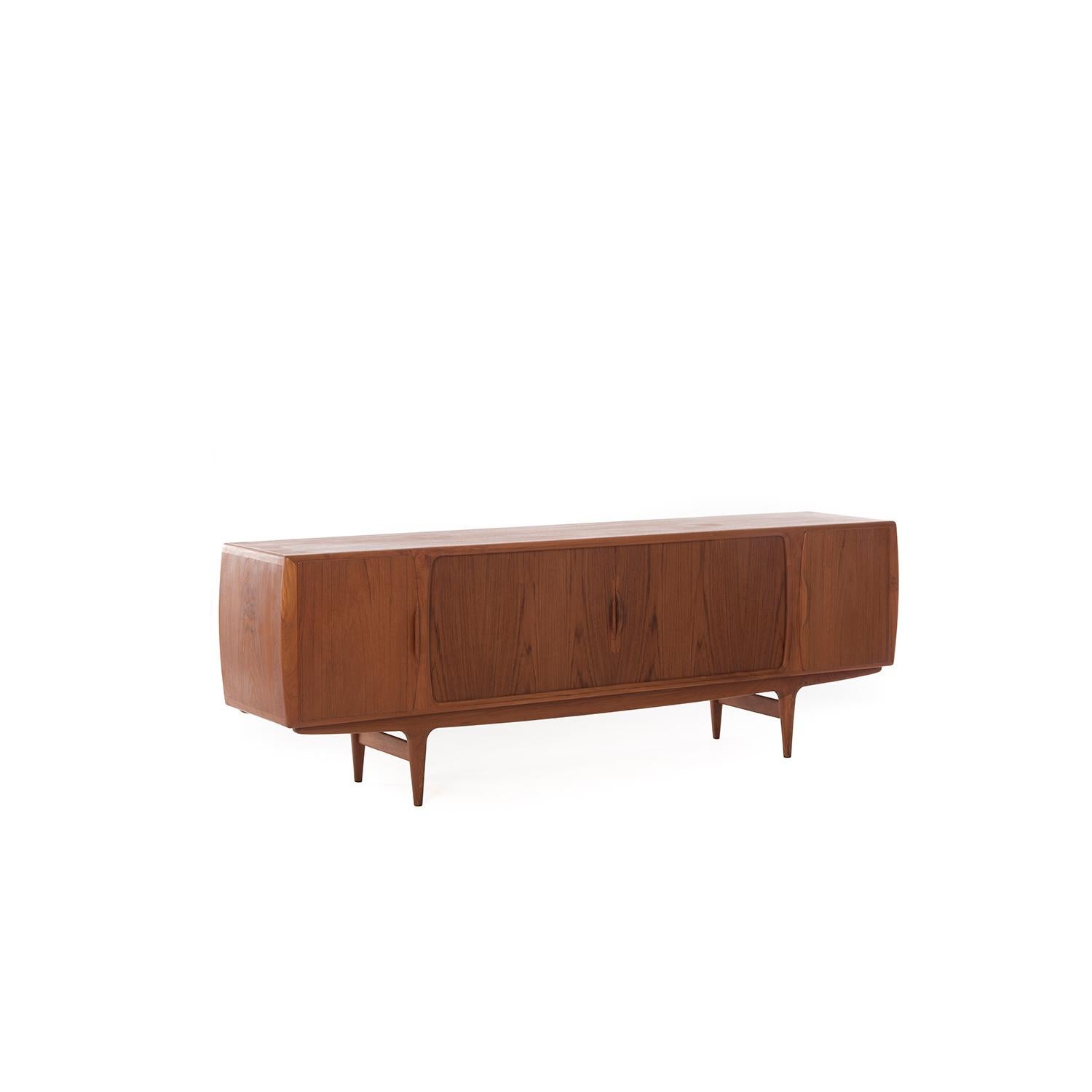 Danish Modern Classic credenza designed by Johannes Andersen. Oiled teak with adjustable shelves and pullout / pull-out lined silver drawers. Central doors are tambour style, outer doors are cupboard style.