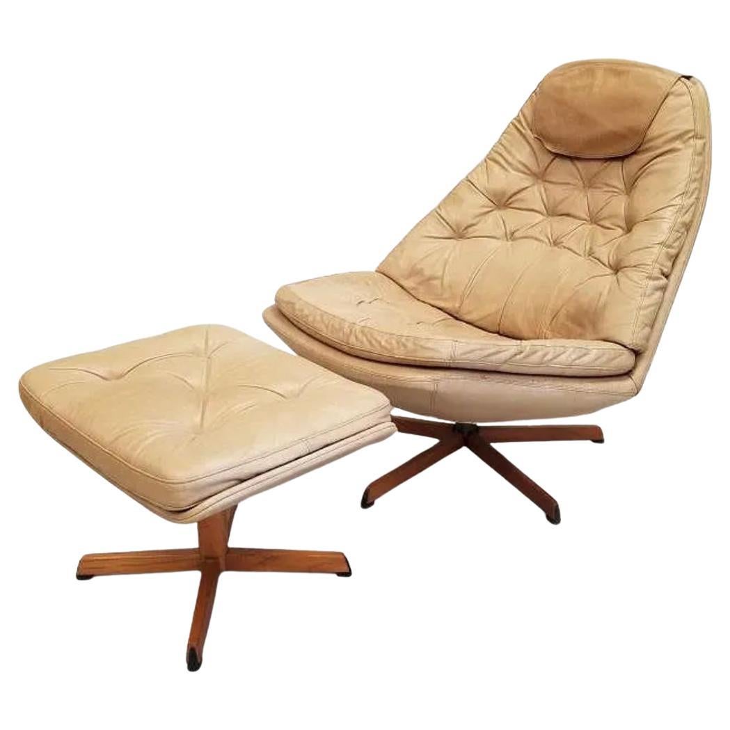 Sillón giratorio de cuero danés moderno Madsen & Schubell con otomana. Estupenda silla y otomana de diseño escandinavo con cojines de piel tostada y respaldo de piel con revestimiento de roble. Muestra un desgaste normal por el uso y la edad - silla