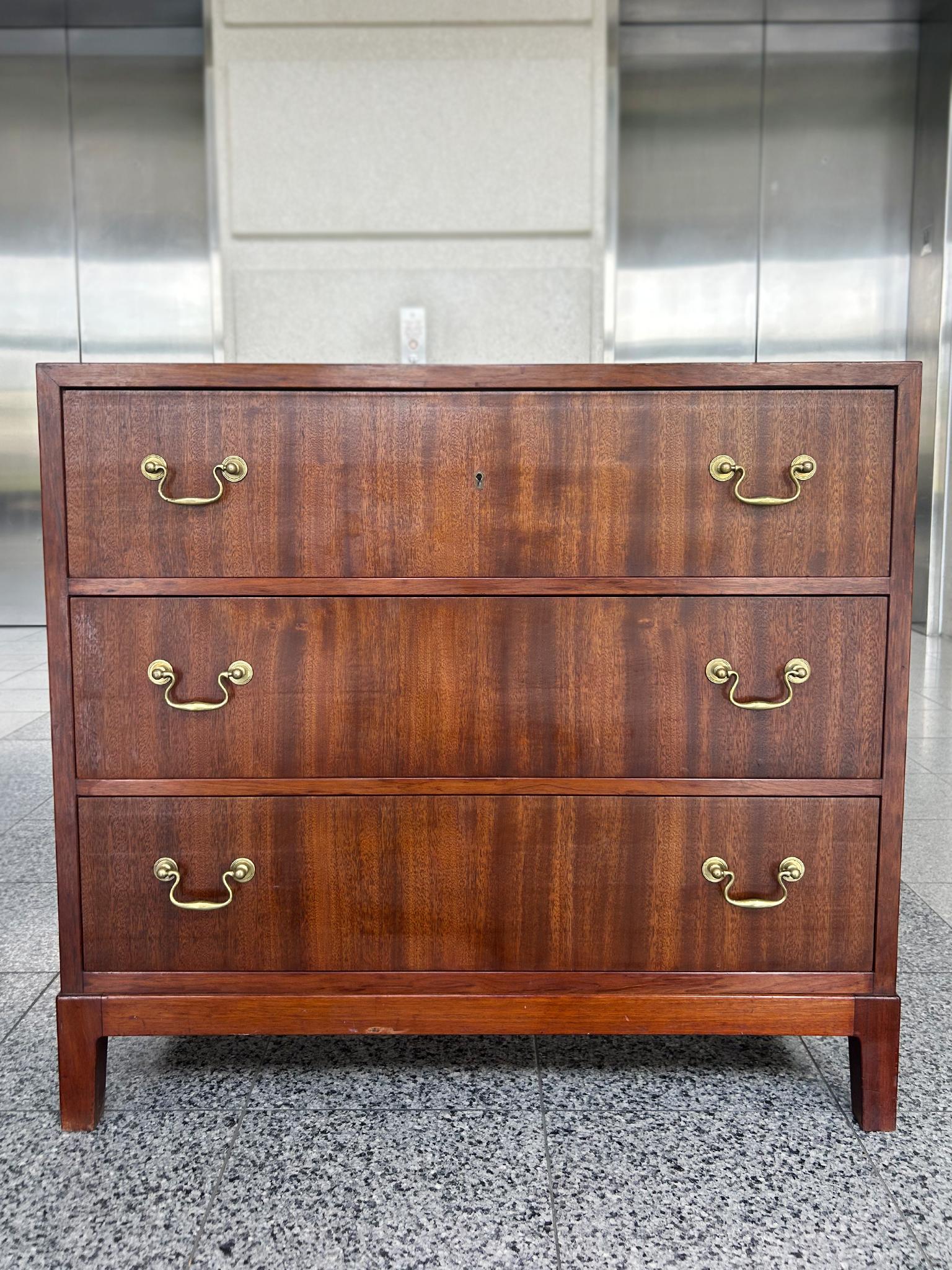 Diseñado en la década de 1940 por Ole Wanscher para A.J. Iversen, esta cómoda moderna danesa está hecha de madera de caoba y tiradores de latón. La madera tiene un rico tono marrón rojizo y sus vetas naturales actúan como sutil ornamentación en un