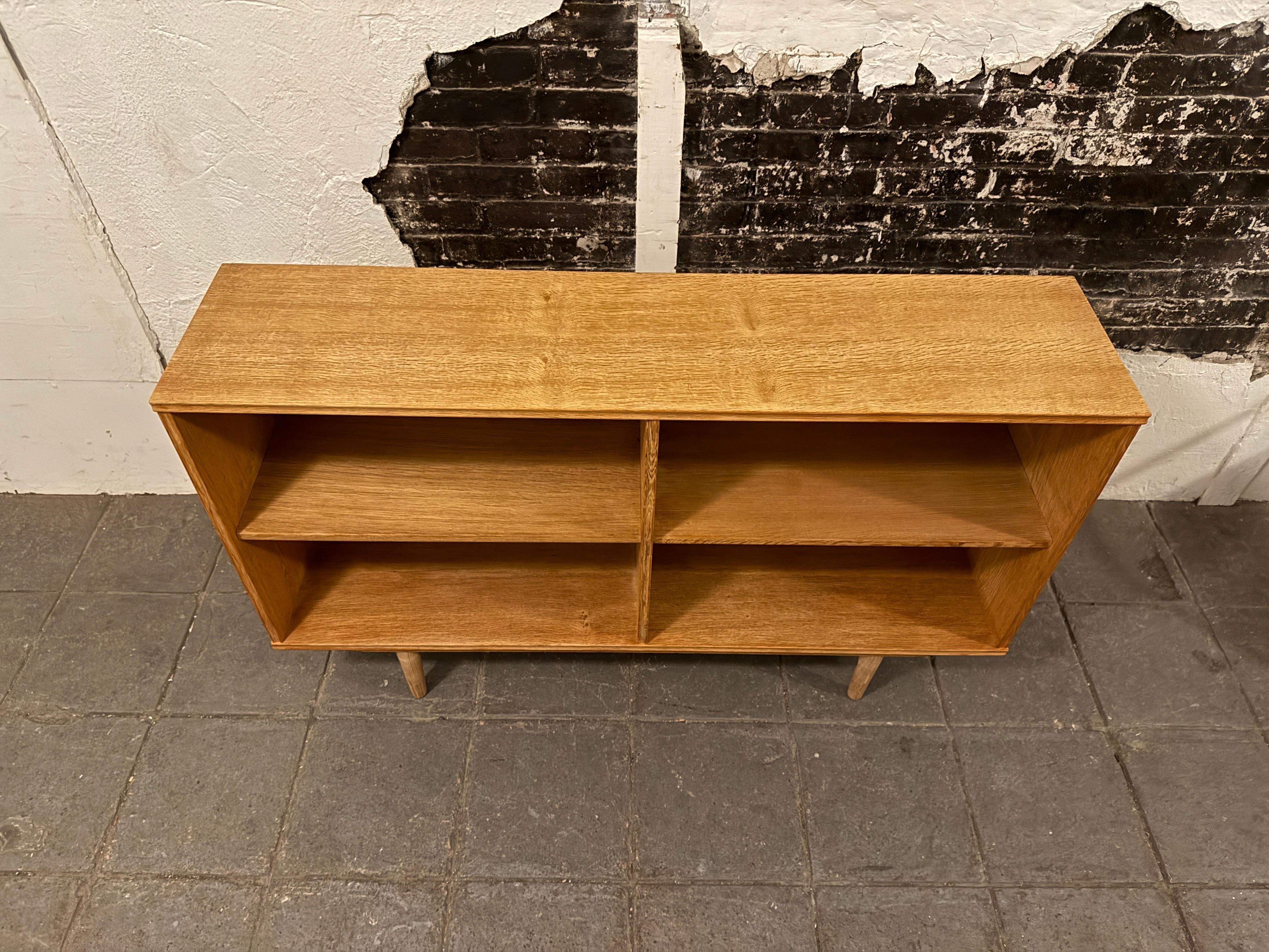 Bellissima e semplice libreria danese moderna di metà secolo lunga e bassa in Oak. Ha 2 ripiani regolabili. Incredibile venatura del rovere chiaro con dettagli sui bordi In ottime condizioni vintage, circa 1960 - prodotto in Danimarca.

Misure 54
