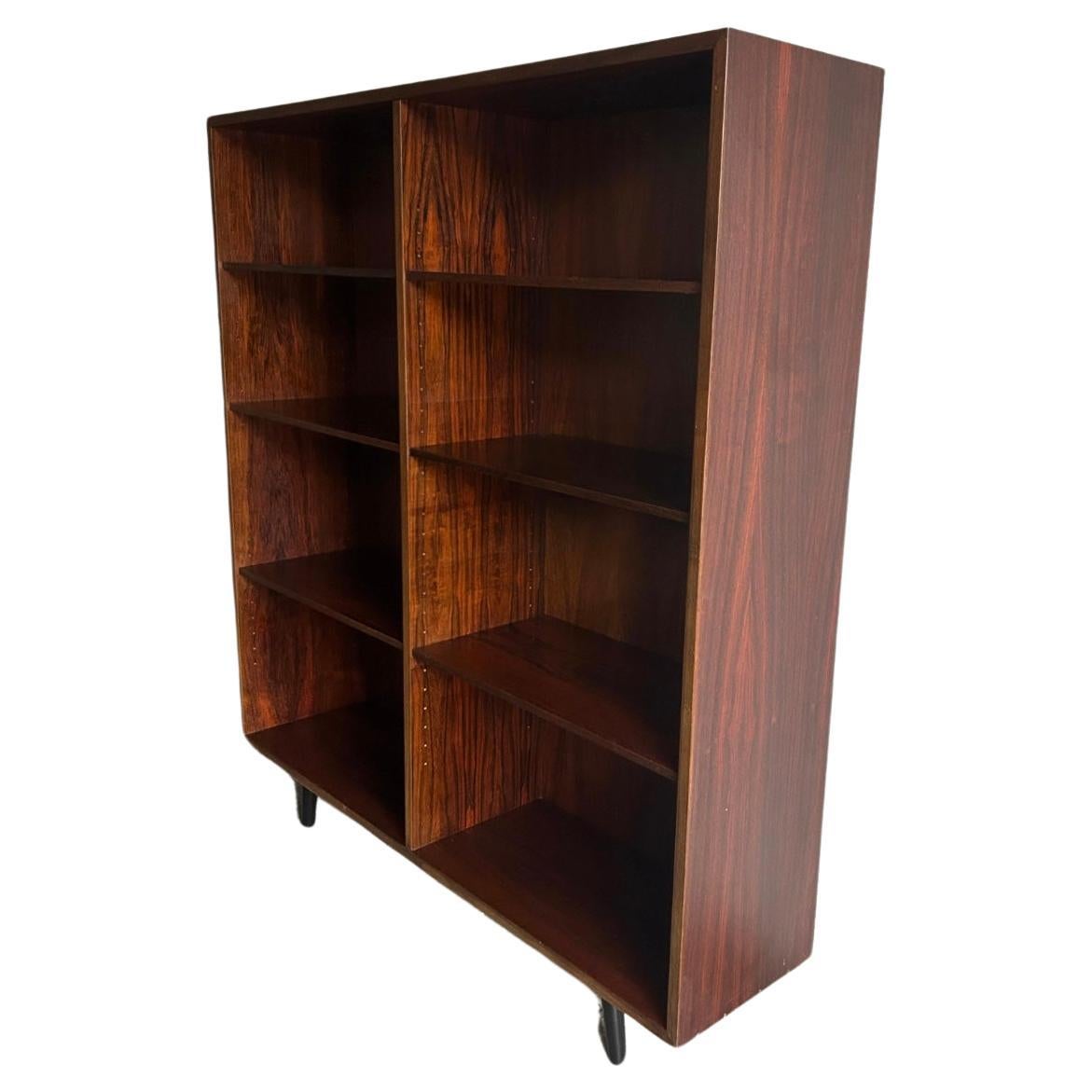 Beautiful simple Danish modern mid century rosewood wide wall floor bookcase. Has 6 adjustable shelves. Amazing rosewood grain! In great vintage condition, circa 1960. Labeled Gunni Omann - made in Denmark.

Measures 47” w x 11.5” d x 53” high