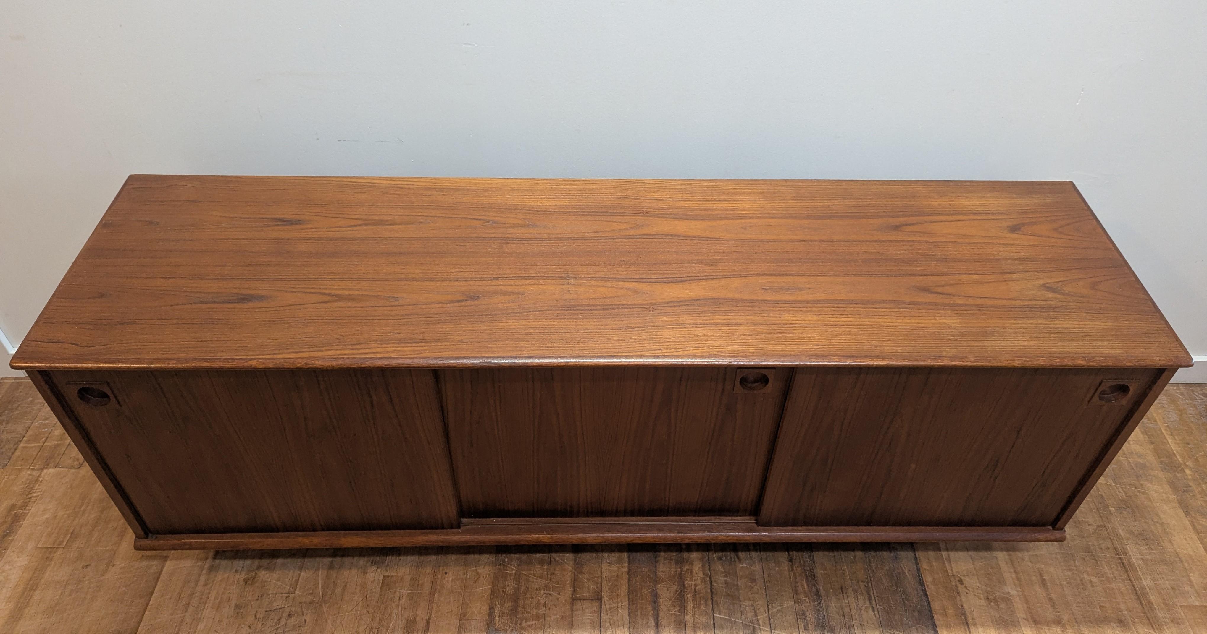 Scandinavian Mid Century Modern Teak Credenza Sideboard by Dyrlund of Denmark.  Danish Modern Teak Credenza Sideboard by Dyrlund having the perfect style, look and functionality that is iconic to Danish Mid Century Modern furniture.  Set on plinth