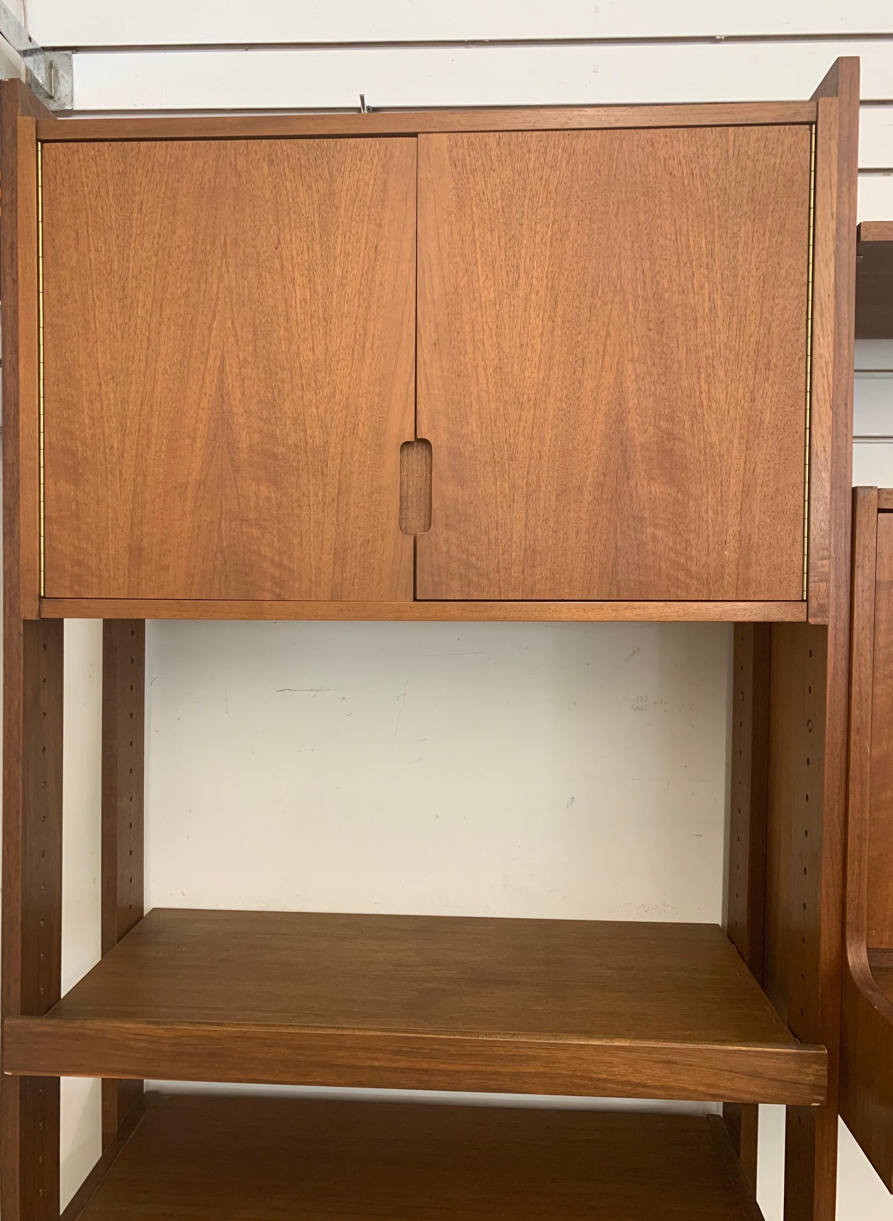 Coveted Danish modern three-bay wall unit with adjustable shelves. This wall unit is finished on all sides and can be used as a room divider or against the wall. Storage options abound with shelves, cabinets and a pull down desk which can be