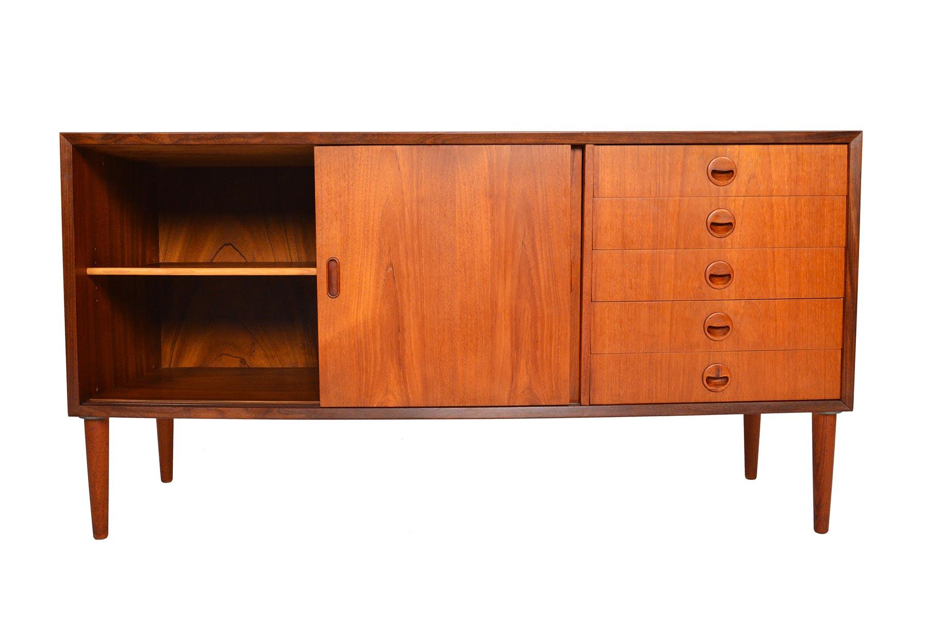 Perfectly sized for modern living, this Danish modern teak credenza was designed with functionality in mind. Two sliding doors open to reveal a large cabinet with an adjustable shelf. A bank of five drawers sit to the right. In excellent original