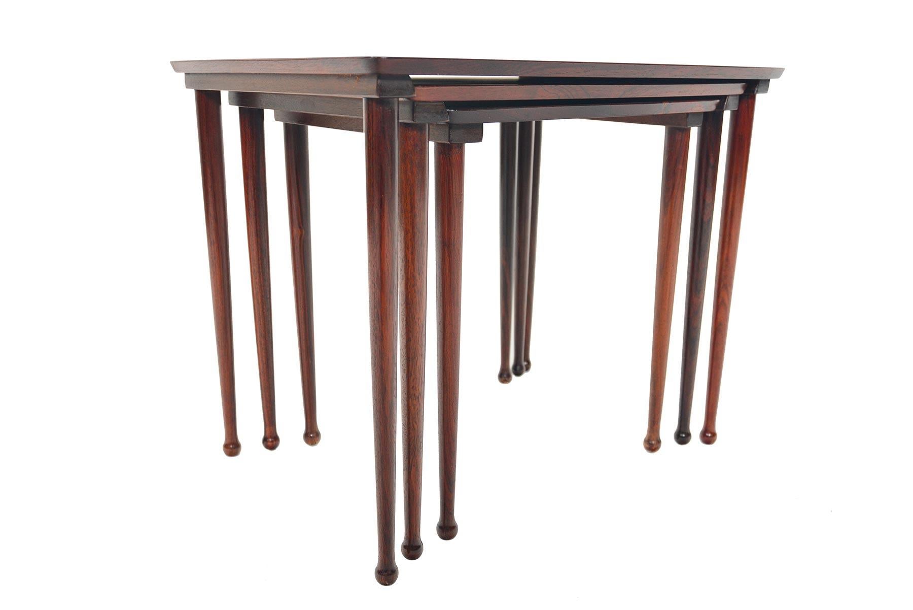 This beautiful set of Danish modern midcentury nesting tables by Mobelintarsia in rosewood will make a fantastic addition to any home. Beautifully tapered legs keep this set simple and elegant, complimented by a softly bowed rectangular table tops.