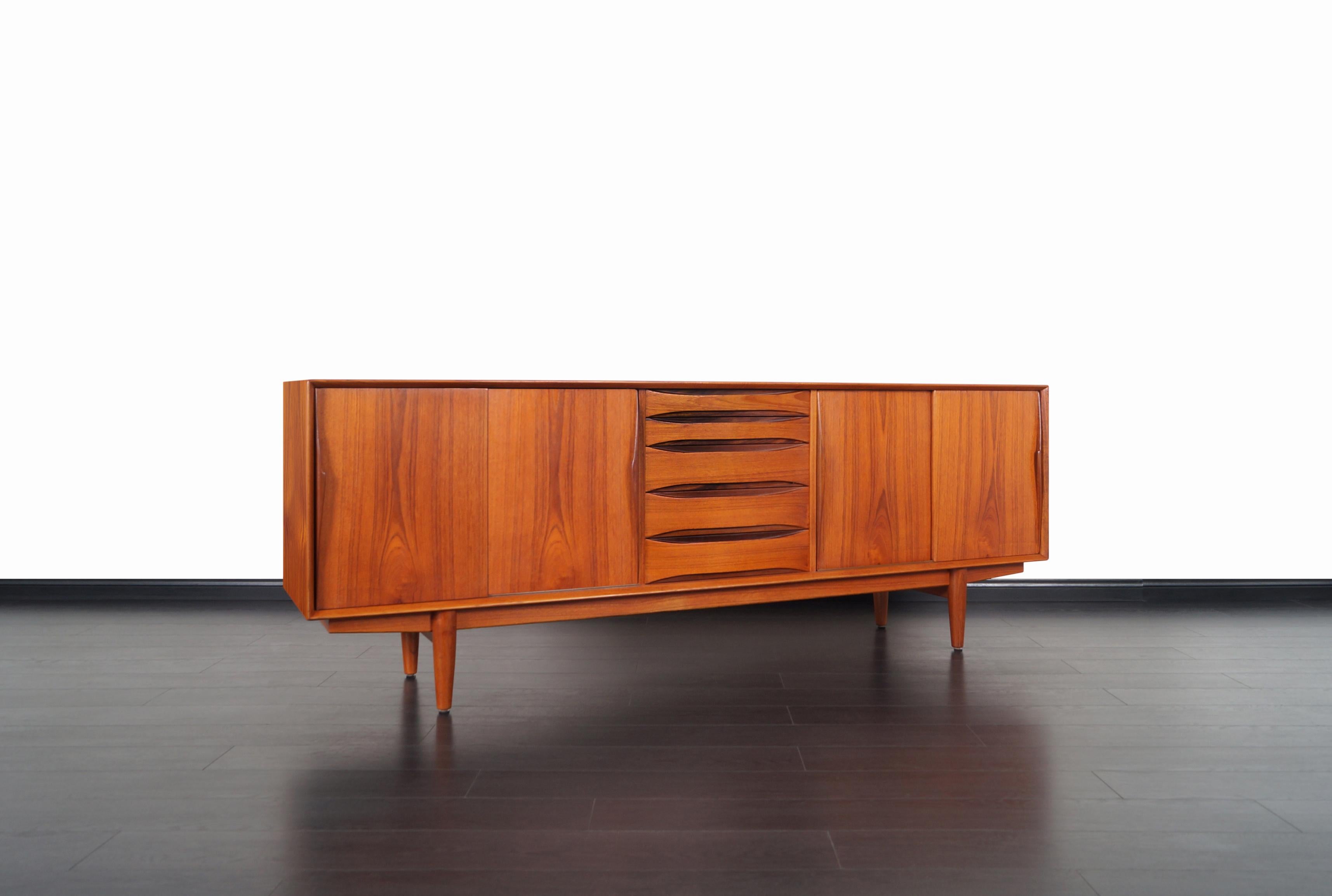 Exceptional Danish modern teak credenza designed by Henry Rosengren Hansen for Skovby Møbelfabrik in Denmark. This skillfully crafted credenza, also known as model #63, features four sliding doors with adjustable shelves and five dovetailed drawers