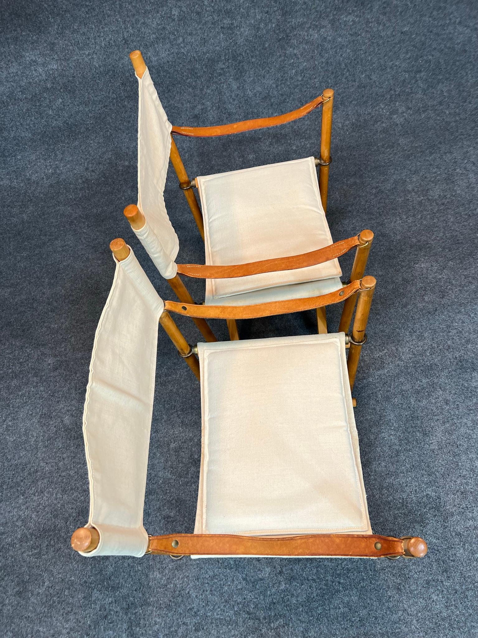 Pair of Danish Modern folding safari chairs (Model MK-16) designed by Mogens Koch in 1932, one manufactured by Rud. Rasmussen and the other by Cado. Made in natural beech wood and brass. Back, seat and cushions in light canvas. Armrests in full