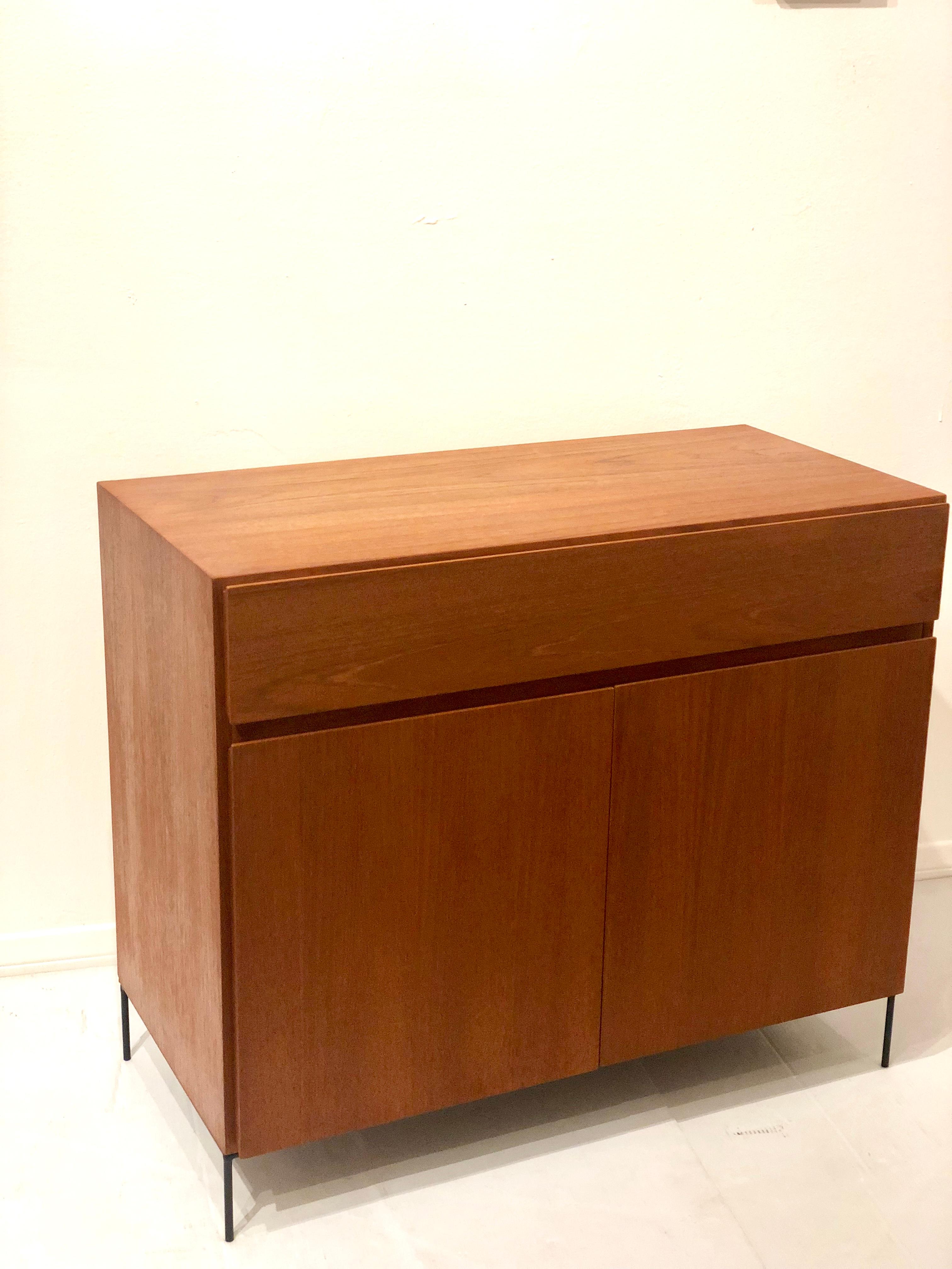 Versatile petite cabinet, circa 1950s made in Denmark, double door and top drawer with small drawers and shelf on the bottom freshly refinished, sitting on solid iron tube base, circa 1960s.