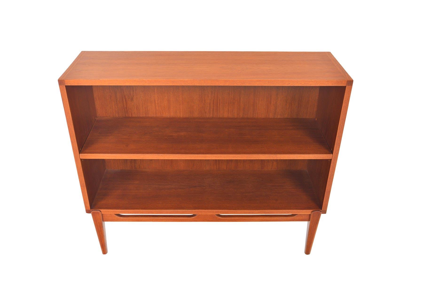 This small Danish modern teak bookcase is a perfect storage solution for any modern home. This piece features a narrow profile, open interior, and an adjustable shelf. Piece stands on a removable tapered base. Recently refinished and in excellent