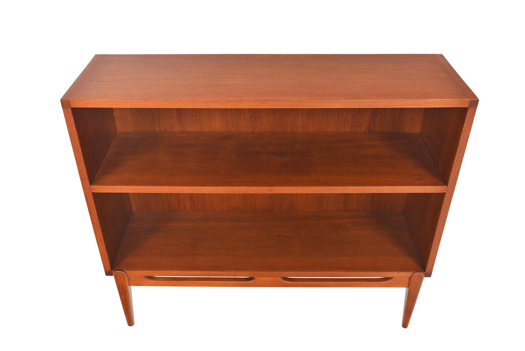 This small Danish modern teak bookcase is a perfect storage solution for any modern home. This piece features a narrow profile, open interior, and an adjustable shelf. Piece stands on a removable tapered base. Recently refinished and in excellent