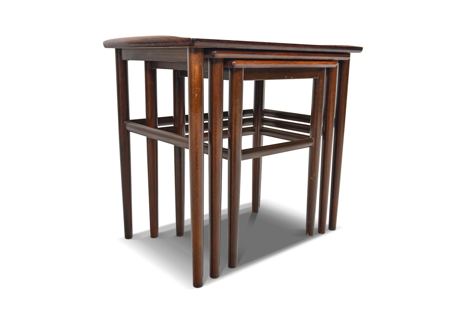 This beautiful set of Danish modern midcentury nesting tables in rosewood by Heltborg will make a fantastic addition to any home. Beautifully tapered legs keep this set simple and elegant, complimented by a softly banded rectangular table tops. In