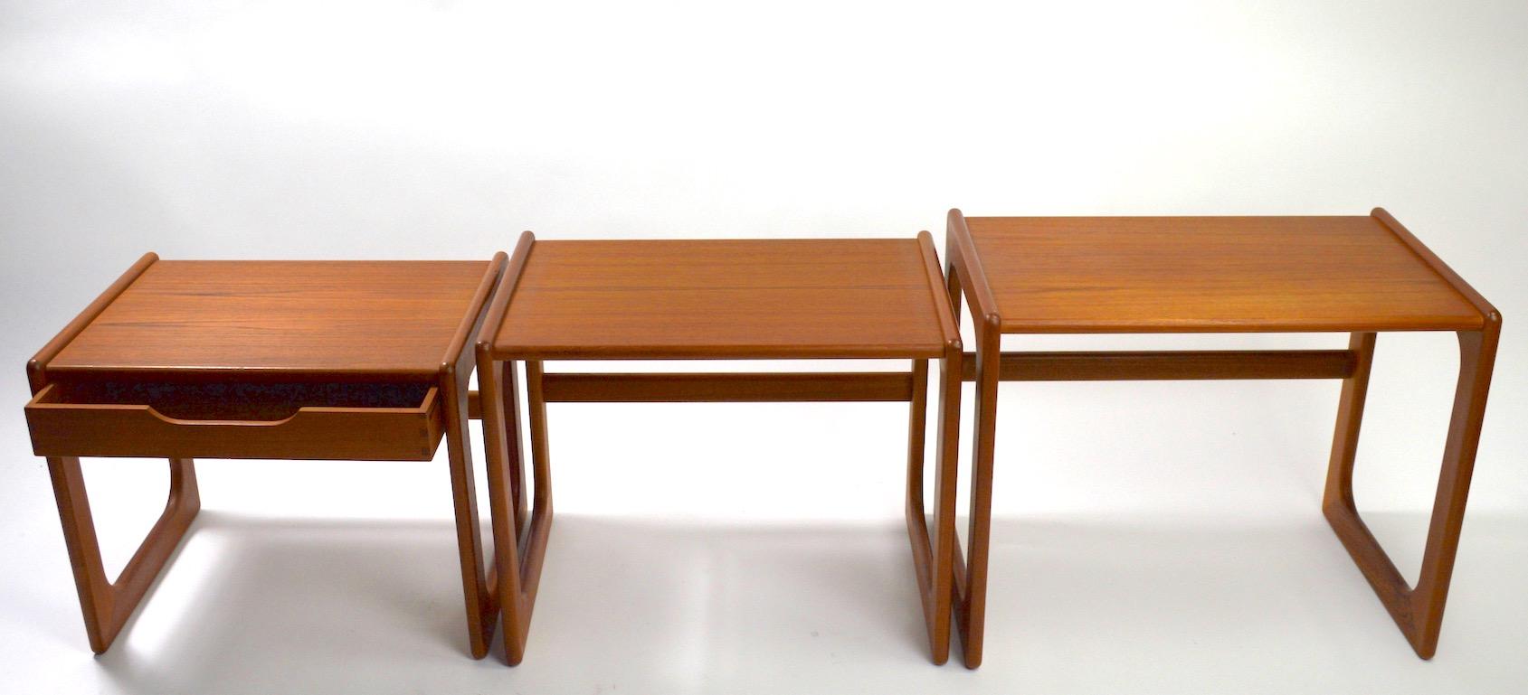 Nice set of three graduated nesting tables made in Denmark. Original, clean, ready to use condition, the smallest table has a drawer, unusual form, not often seen in these sets. Manufacture attributed to Dyrlund, however it is unsigned. Dimensions