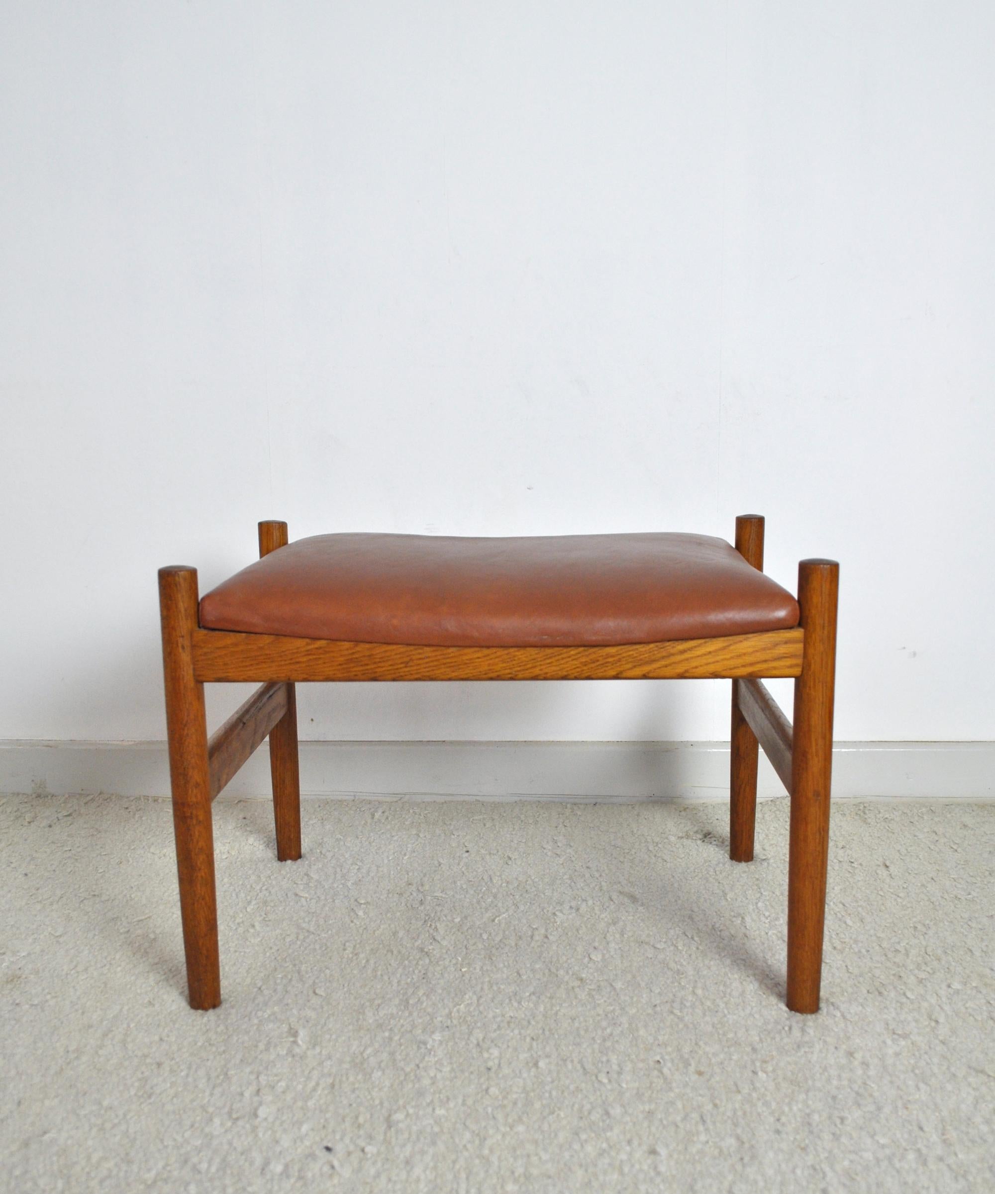 Danish midcentury ottoman or stool, solid oak frame and gently refurbished brown original leather cushion. Produced by Hugo Frandsen, Spøttrup 1960s.