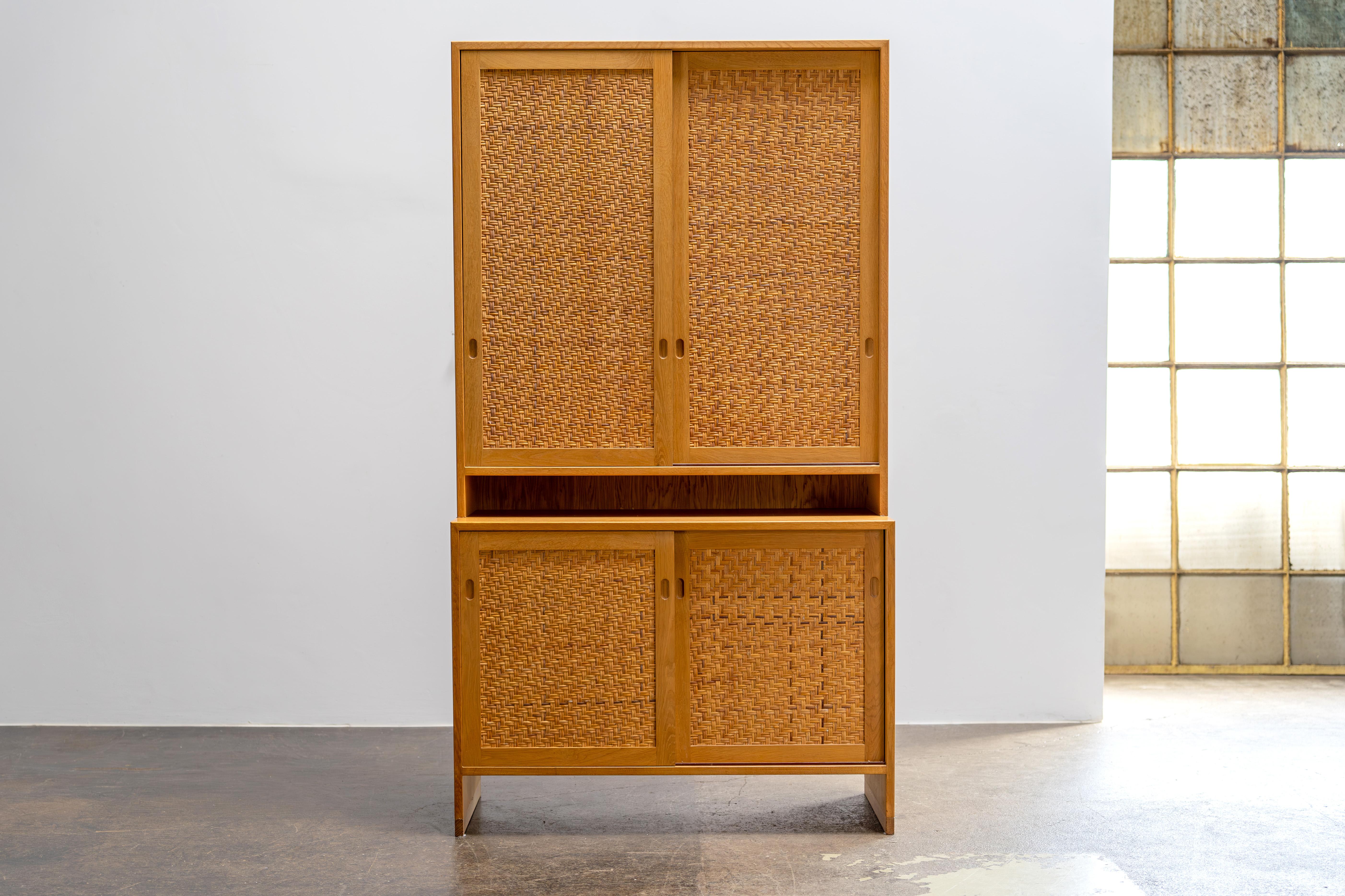 Questo mobile alto di Hans Wegner per Ry Møbler è caratterizzato da eleganti ante in rattan e da un corpo in rovere massiccio con interni di ottima fattura. Progettata all'inizio degli anni '60 e prodotta nel 1972, incarna il caratteristico