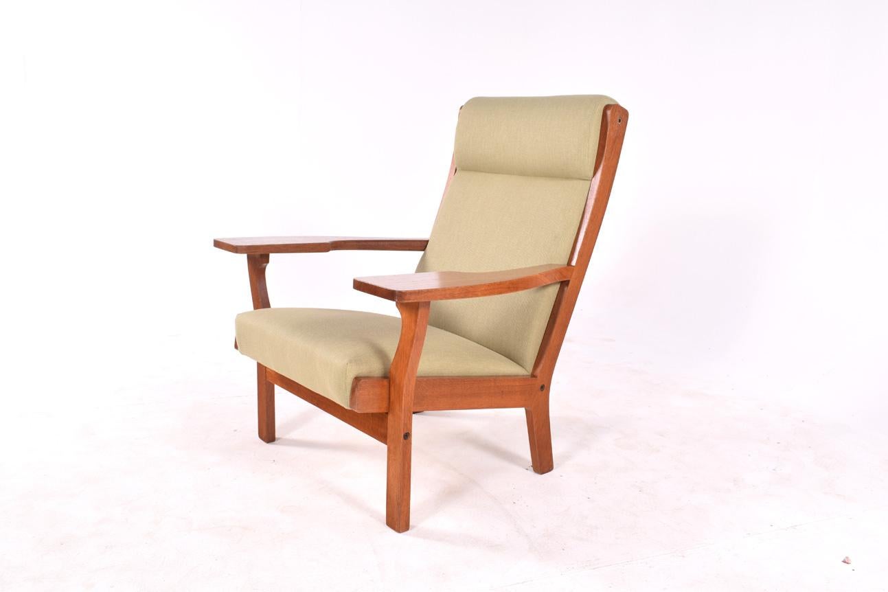 This armchair was designed by Hans Wegner. The chair is made from oak and have just been completely reupholstered with a green fabric. Has a high back plank for best seating comfort, circa 1970.