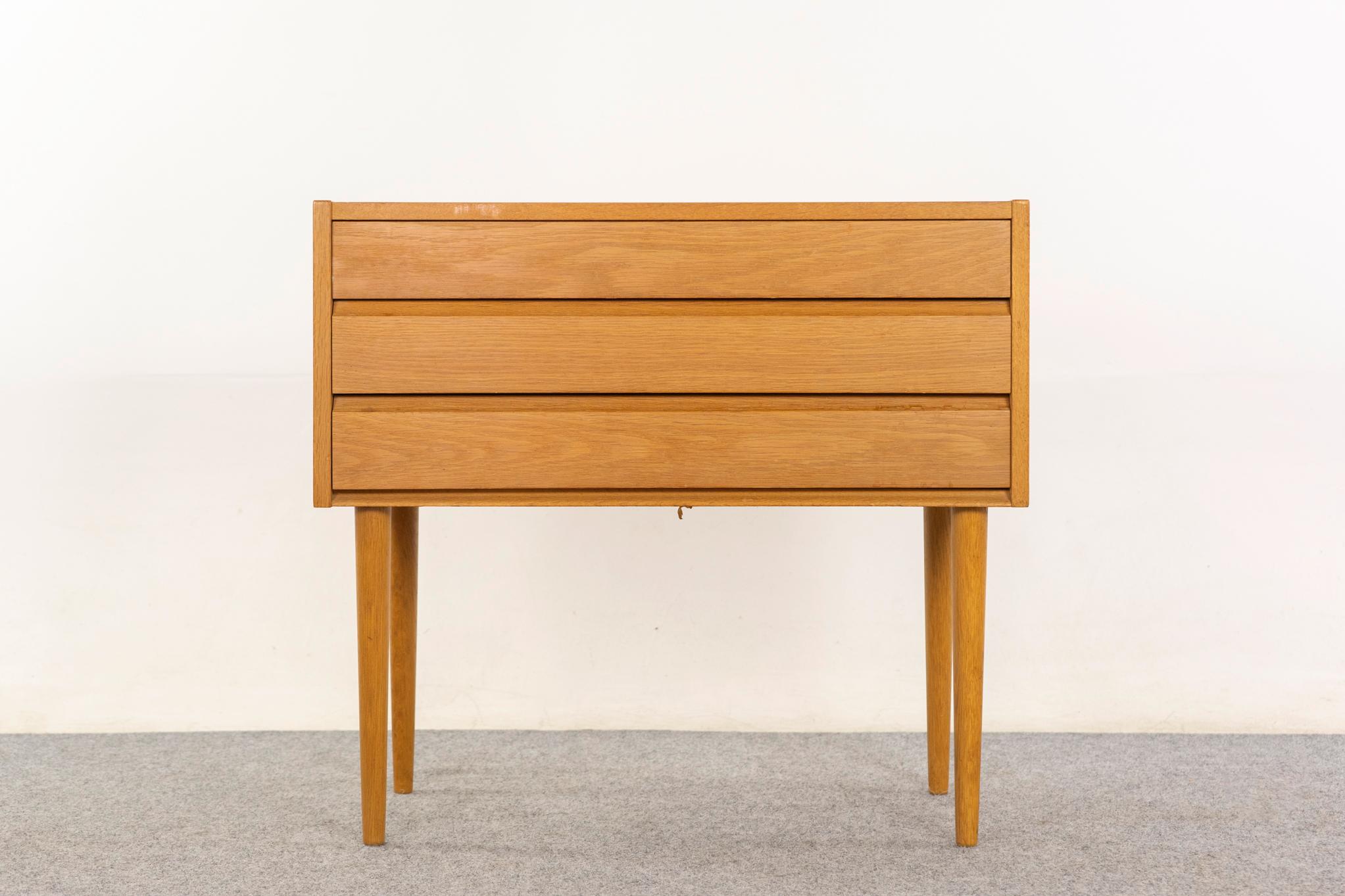 Mesilla de noche danesa de roble, hacia 1960. La caja, bellamente chapada, descansa sobre unas patas esbeltas, cónicas y desmontables. Elegantes cajones con construcción de cola de milano y elegantes tiradores integrados. Excelente