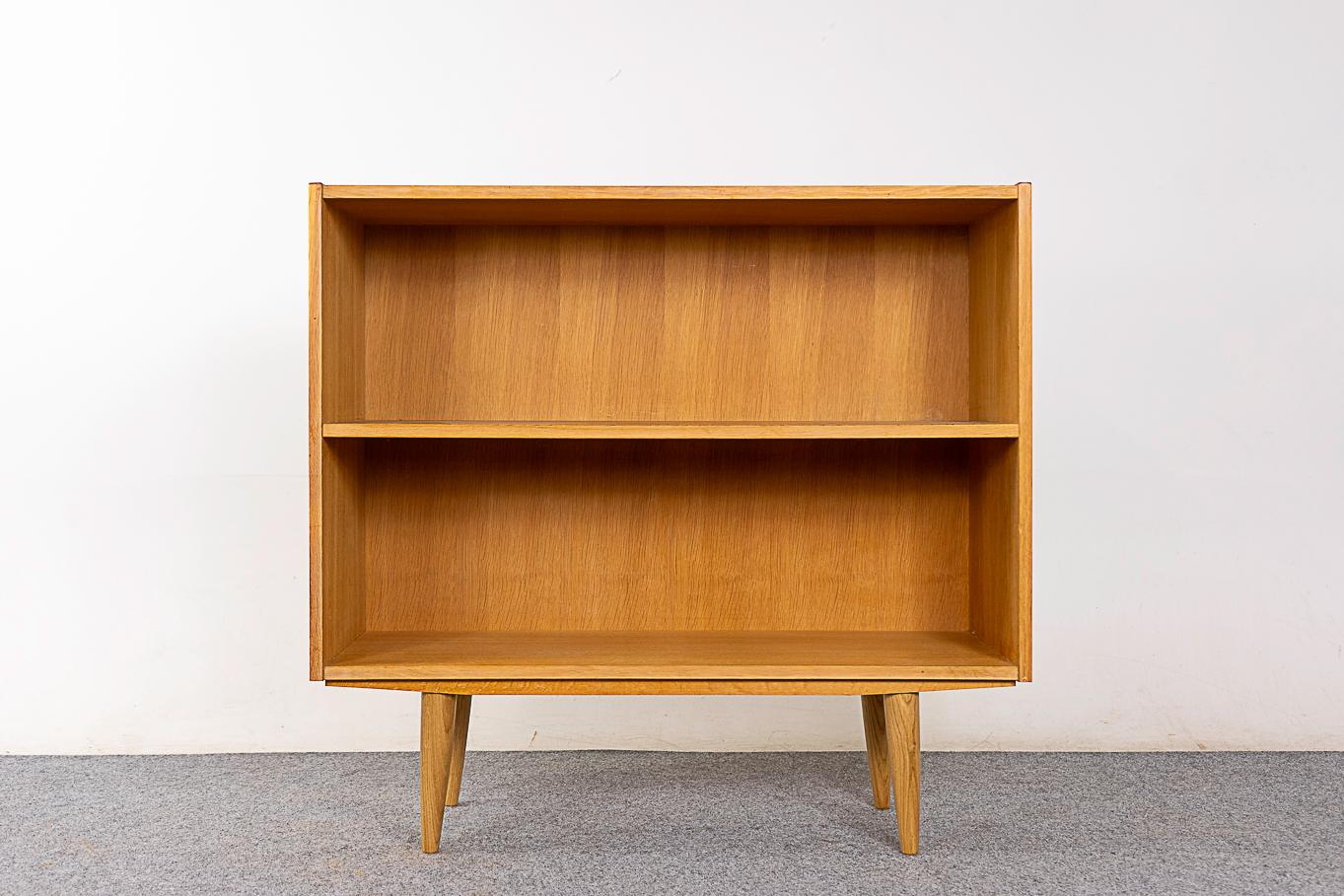 Oak Danish bookcase, circa 1960's. Sleek, low profile lines with fixed height shelf. Bookmatched veneer and solid removable tapered legs . Slim compact size for the modern condo.

Unrestored item with option to purchase in restored condition for an