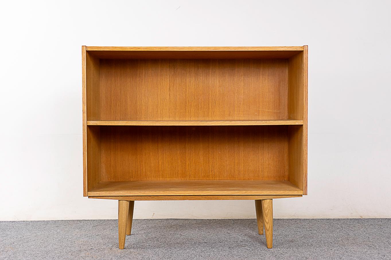 Oak Danish bookcase, circa 1960's. Sleek, low profile lines with fixed height shelf. Bookmatched veneer and solid removable tapered legs . Slim compact size for the modern condo.

Unrestored item with option to purchase in restored condition for an