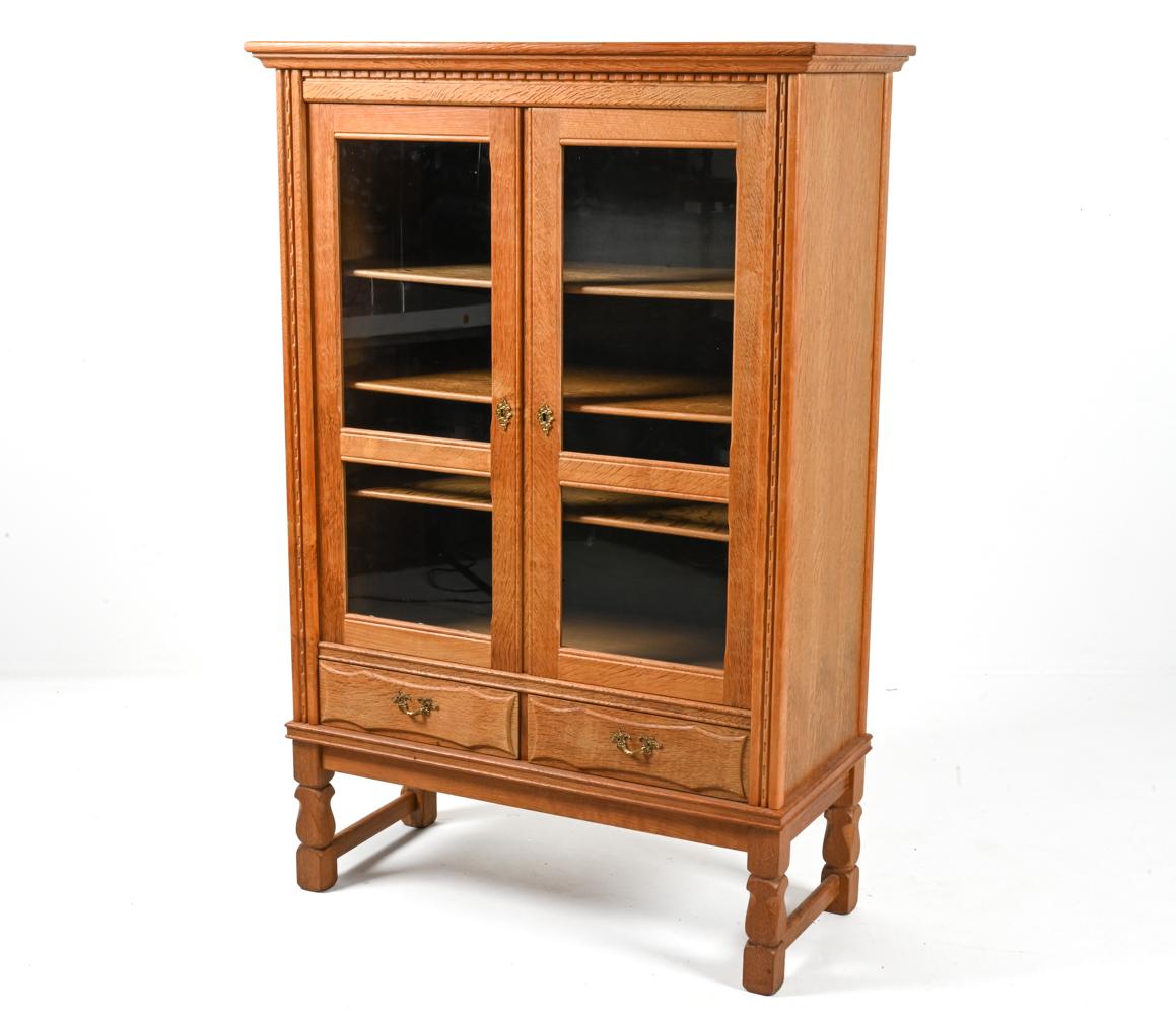 Unusual and highly decorative architectural millwork sets this exceptional Henning Kjærnulf display cabinet apart from the rest. Classic dentil carving underlines the crown, while the sides are trimmed with rounded molding carved at intervals with