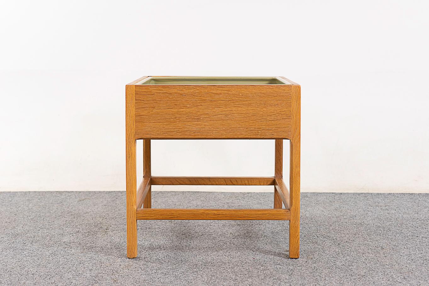 Oak mid-century planter by Kai Kristiansen for Aksel Kjersgaard, circa 1960's. Solid oak legs and crossbars, veneer constructed flat surfaces. Unique bevelled cubic underframe and original plastic lining with wear. 