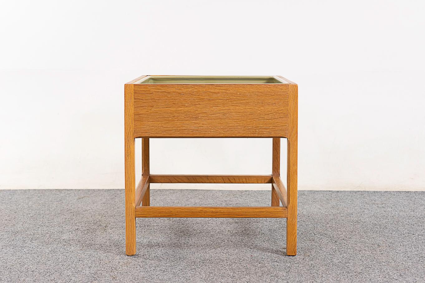 Oak mid-century planter by Kai Kristiansen for Aksel Kjersgaard, circa 1960's. Solid oak legs and crossbars, veneer constructed flat surfaces. Unique bevelled cubic underframe and original plastic lining with wear. 
