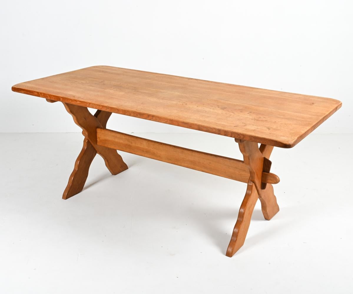 Créez un espace de repas Farmhouse Modern serein avec cette table attribuée à l'inimitable Henning Kjærnulf. Fabriquée en magnifique chêne blanc scié sur quartier, cette table présente un élégant piètement en X avec des festons sculptés sur les
