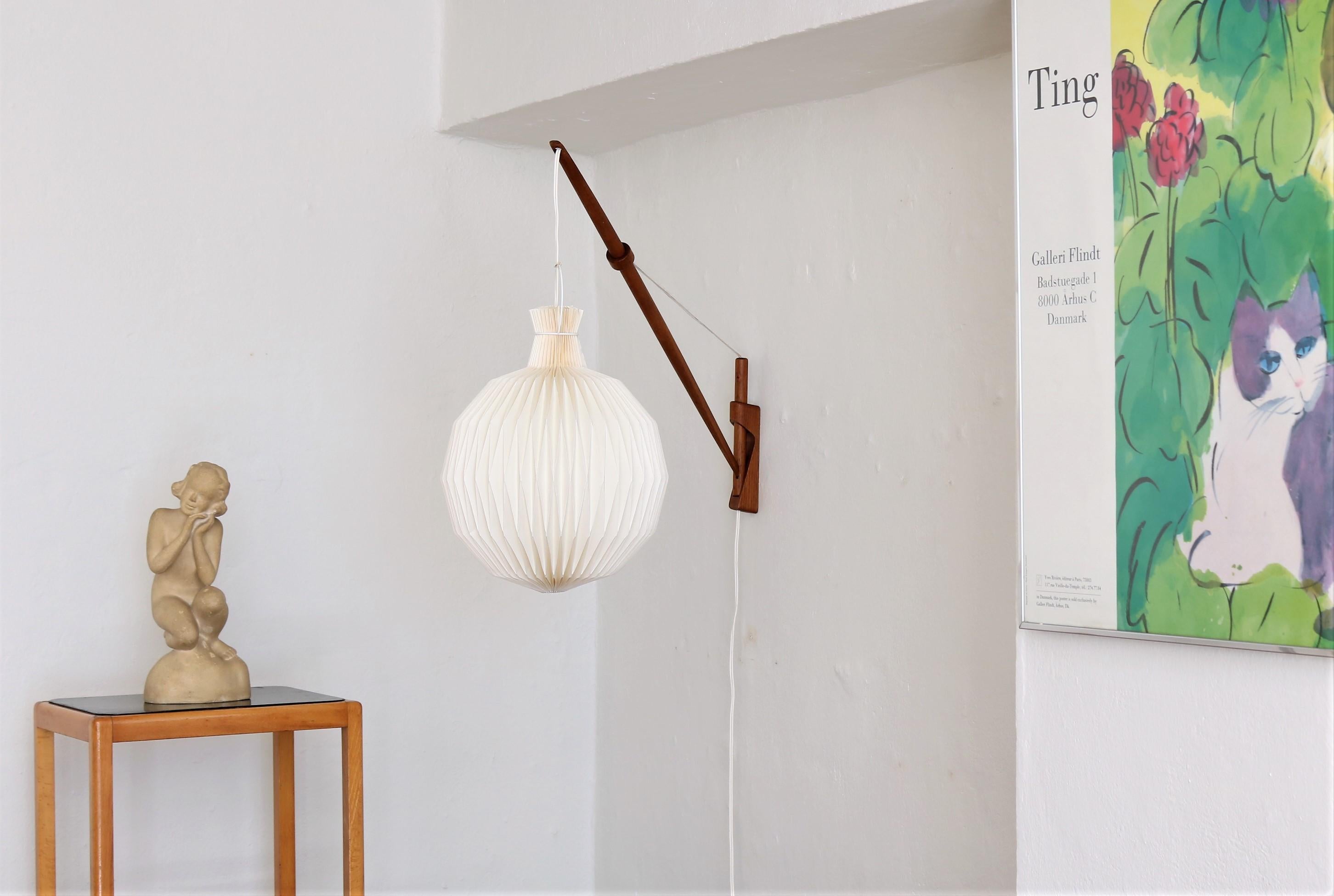 This lamp is an amazing piece of Danish modern design. The wall lamp is in patinated oak and was made in the 1950s by designers A. Bank Jensen & Kjeld Iversen for Louis Poulsen. The lamp can be adjusted in any directions and angles simply by pulling