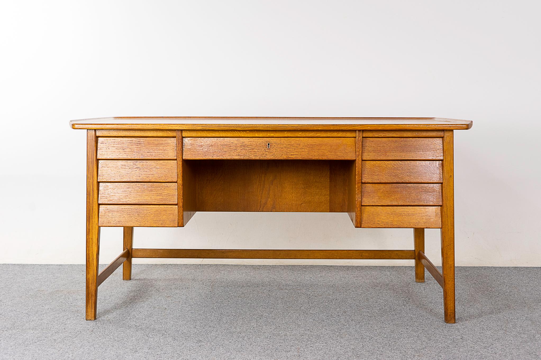 Oak mid-century desk, circa 1960's. Robust desk with curling top edges and ample storage for your essentials. Open book cubby on the back side. Finished on both sides, if placed in the center of a room, it will look fantastic from every angle! Cross