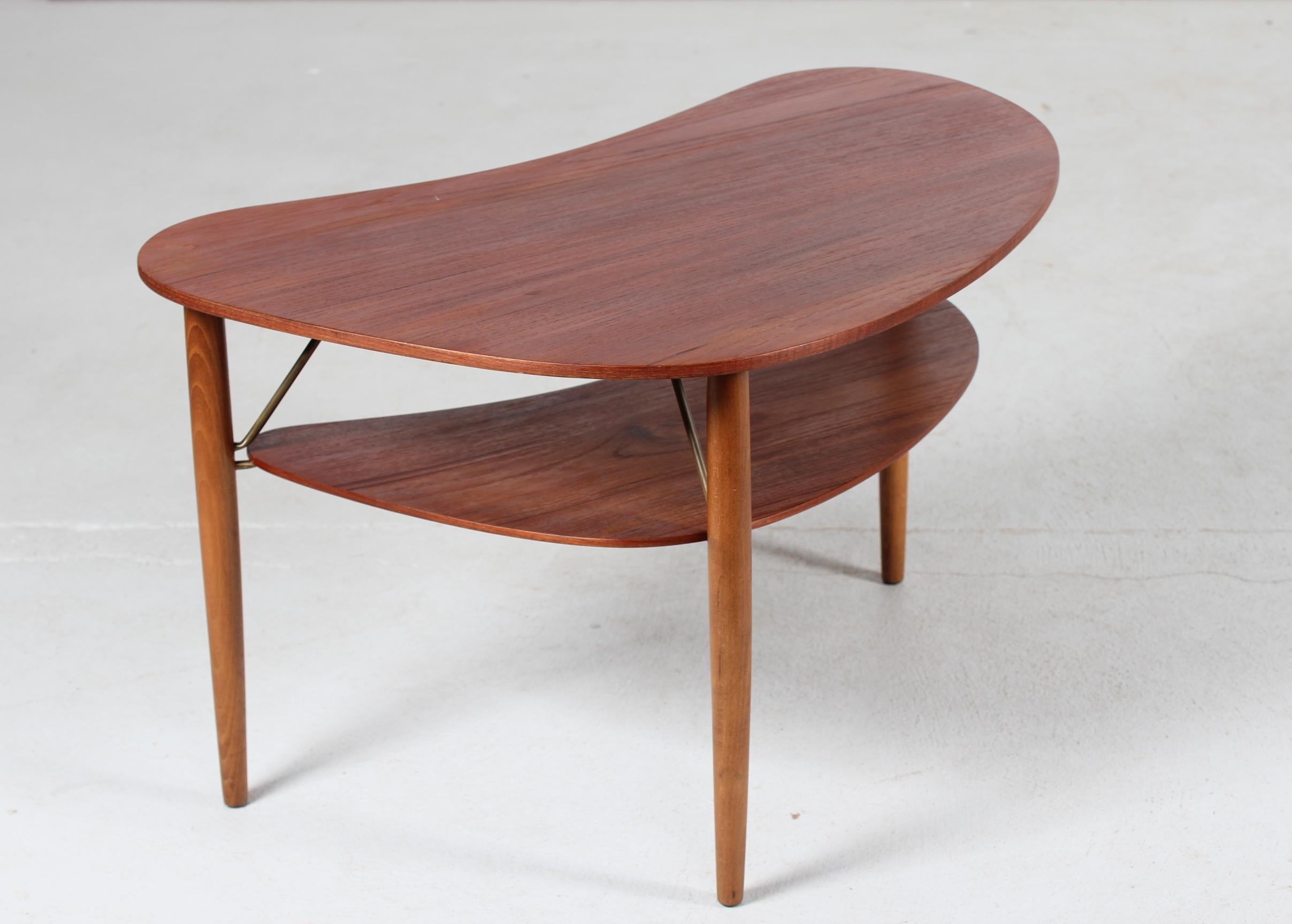 Dänischer moderner organisch geformter Couchtisch mit Regal aus den 1950er Jahren, ein
Vintage-Tisch mit einer schönen runden Form. 
Die Tischplatte ist aus Teakholzfurnier und die runden Beine sind aus massiver Buche gefertigt. Die Beschläge und