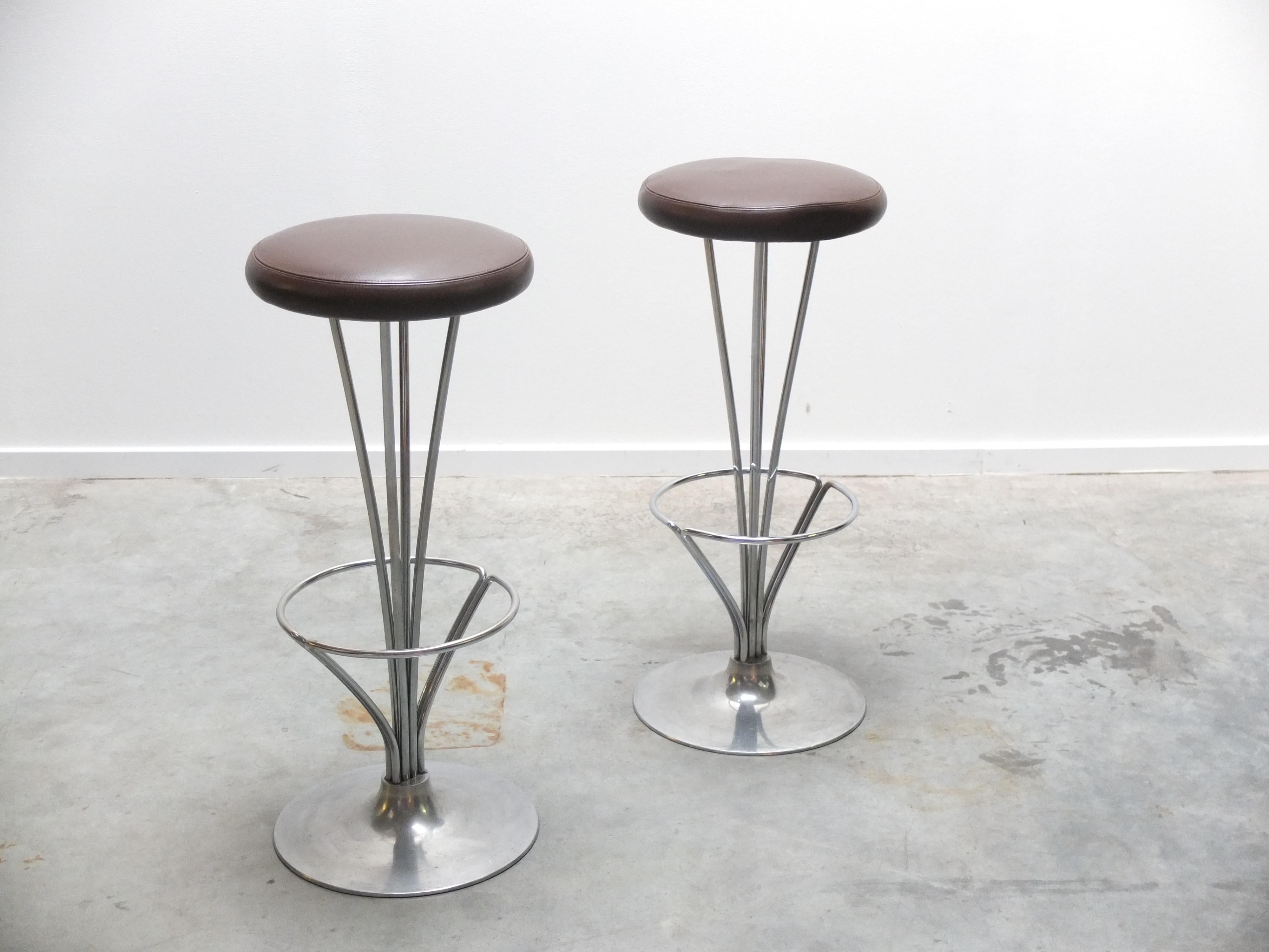 A lovely pair of modernist bar stools designed by Piet Hein during the 1960s. They feature a beautiful chromed steel frame with the original dark brown leather seats. Produced by Fritz Hansen in 1984 (labeled) and in very good condition.