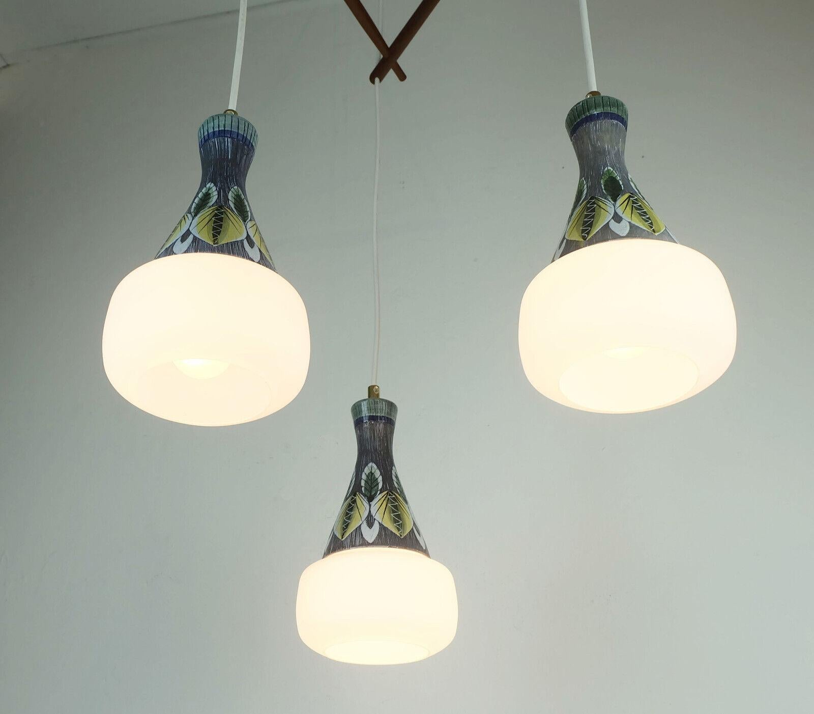 Exceptionnellement belle lampe suspendue des années 1950 au début des années 1960. Origine probablement scandinave. Abat-jours en verre satiné blanc et céramique colorée avec motif de feuilles, entretoises en teck. Fil électrique blanc et auvent