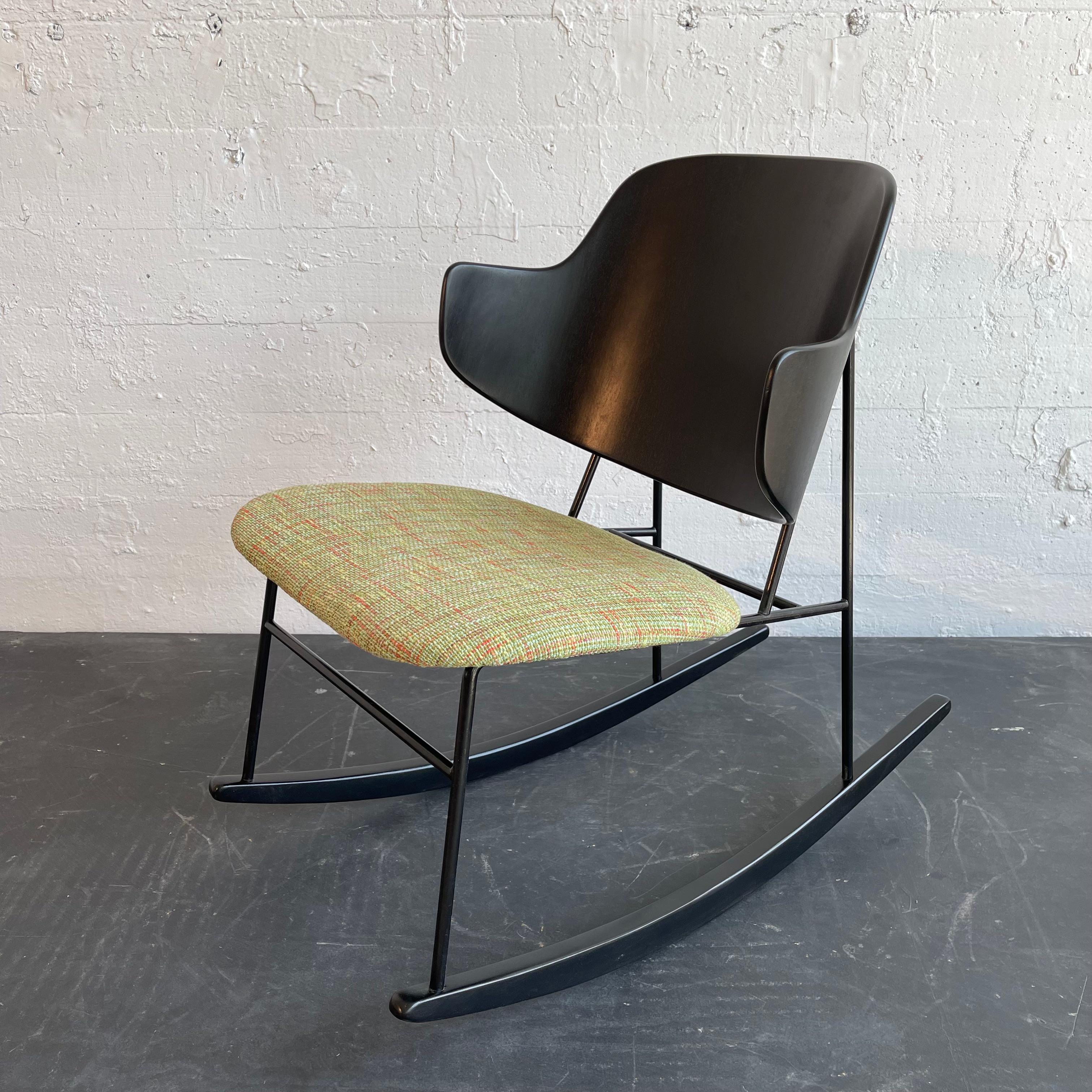 La sedia a dondolo Penguin di Ib Kofod-Larsen, noto designer danese, è una vera e propria testimonianza dell'artigianato scandinavo e presenta uno schienale scultoreo in legno curvato su una struttura in ferro battuto con guide in legno e una seduta