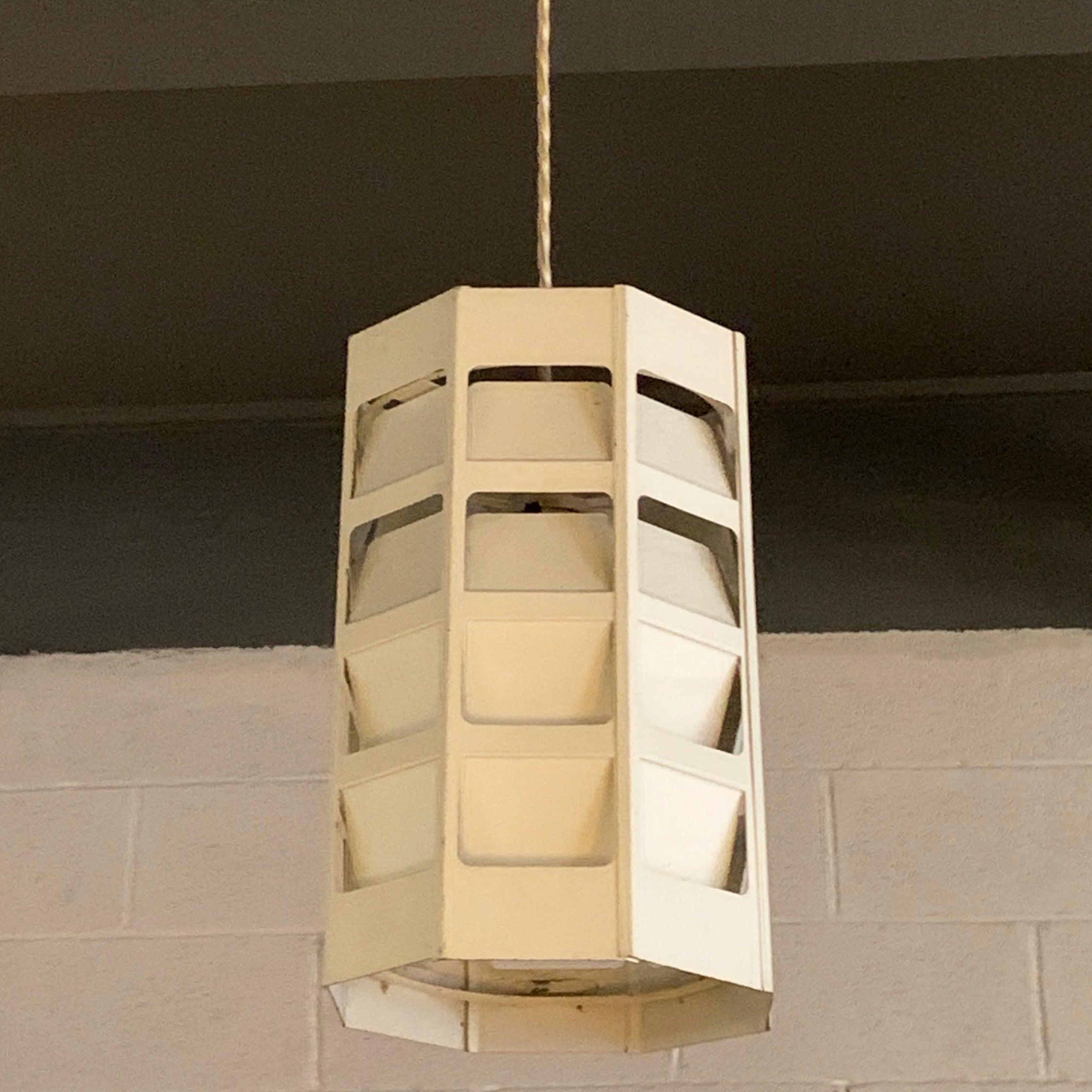 L'étonnante suspension moderne danoise de Poul Gernes pour Louis Poulsen présente un cylindre en métal blanc à facettes qui émet de la lumière à travers ses sections pliées et découpées. Les images montrent le pendentif atténué et complètement
