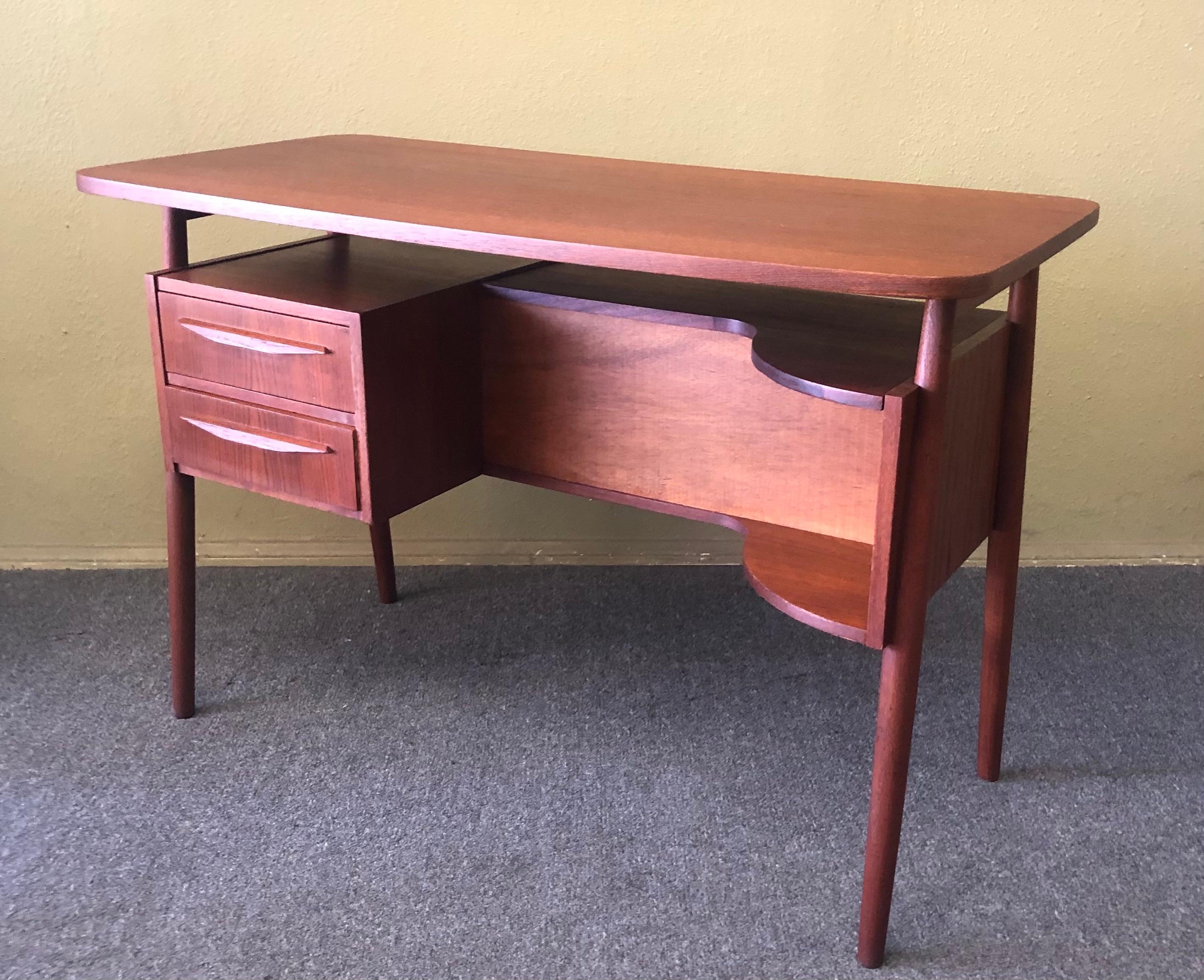 Danish modern petite teak desk by Gunnar Nielsen for Tibergaard, circa 1960s. One bank of two dovetailed drawers sit on the left side of the knee hole providing excellent storage. Finished on all sides, this desk can be floated in the center of any