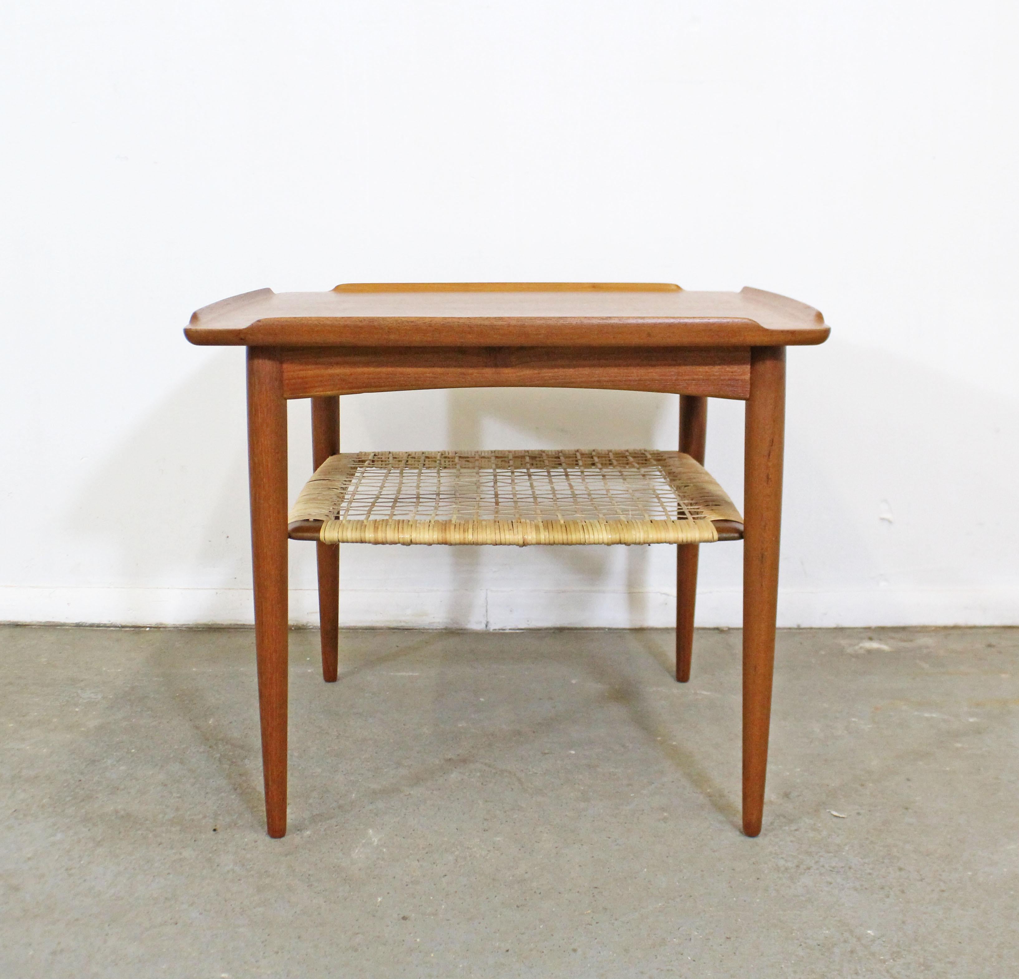 What a find! Offered is a Danish modern square table designed by Poul Jensen for Selig. The table is made of teak with a caned shelf that has been professionally restored. It is in excellent condition with little to no wear. It is not signed. Check