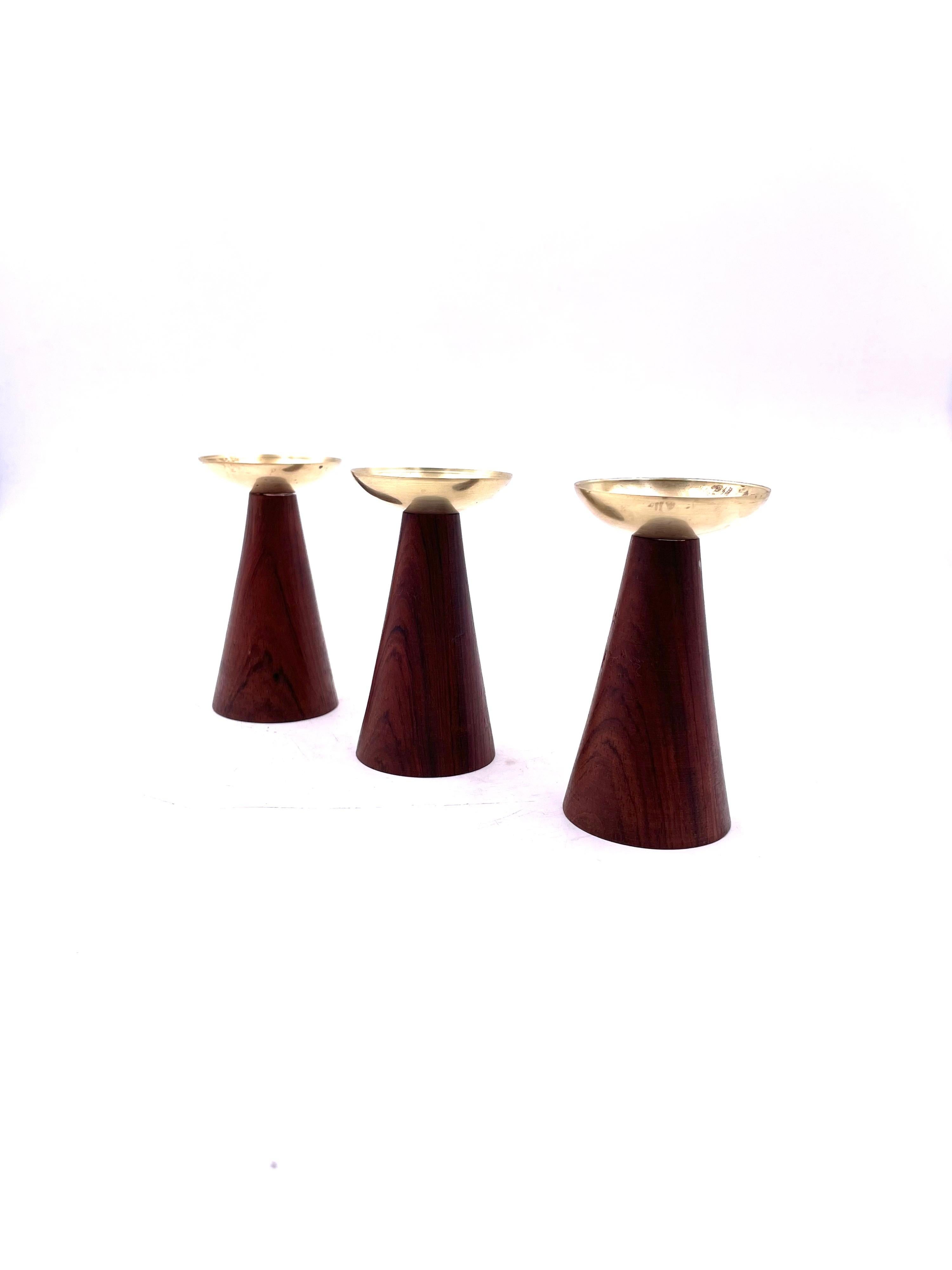Beautiful and rare set of 3 candle holders designed by Hans Agne Jakobsson , made in Sweden circa 1950's solid teak turned base with solid patinated brass, and removable tops that secure with the candles, the set retains its label.