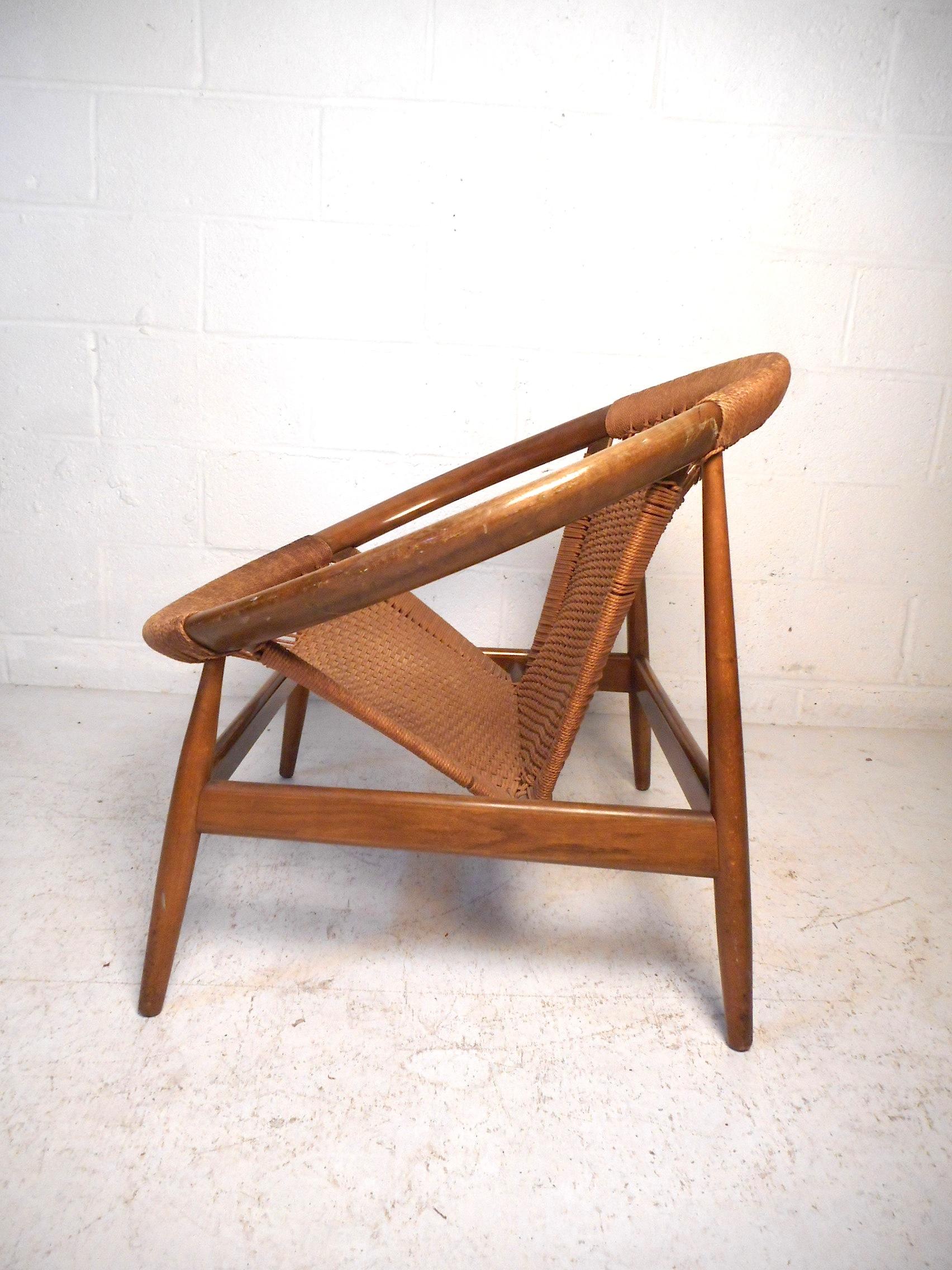 This unique Danish modern hoop chair features a sturdy teak construction, a sleek angular frame which gives the piece an interesting visual profile, and stylishly comfortable woven cord seating. Made in Denmark, circa 1950s. A very unusual and