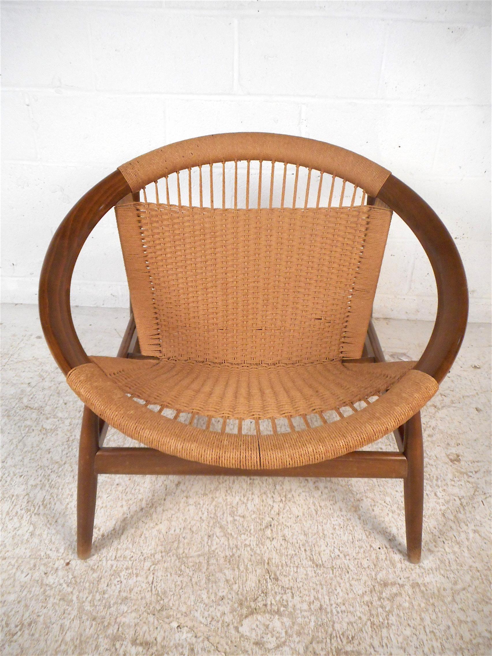 This unique Danish modern hoop chair features a sturdy teak construction, a sleek angular frame which gives the piece an interesting visual profile, and stylishly comfortable woven cord seating. A distinctive and sought after chair, made in Denmark,