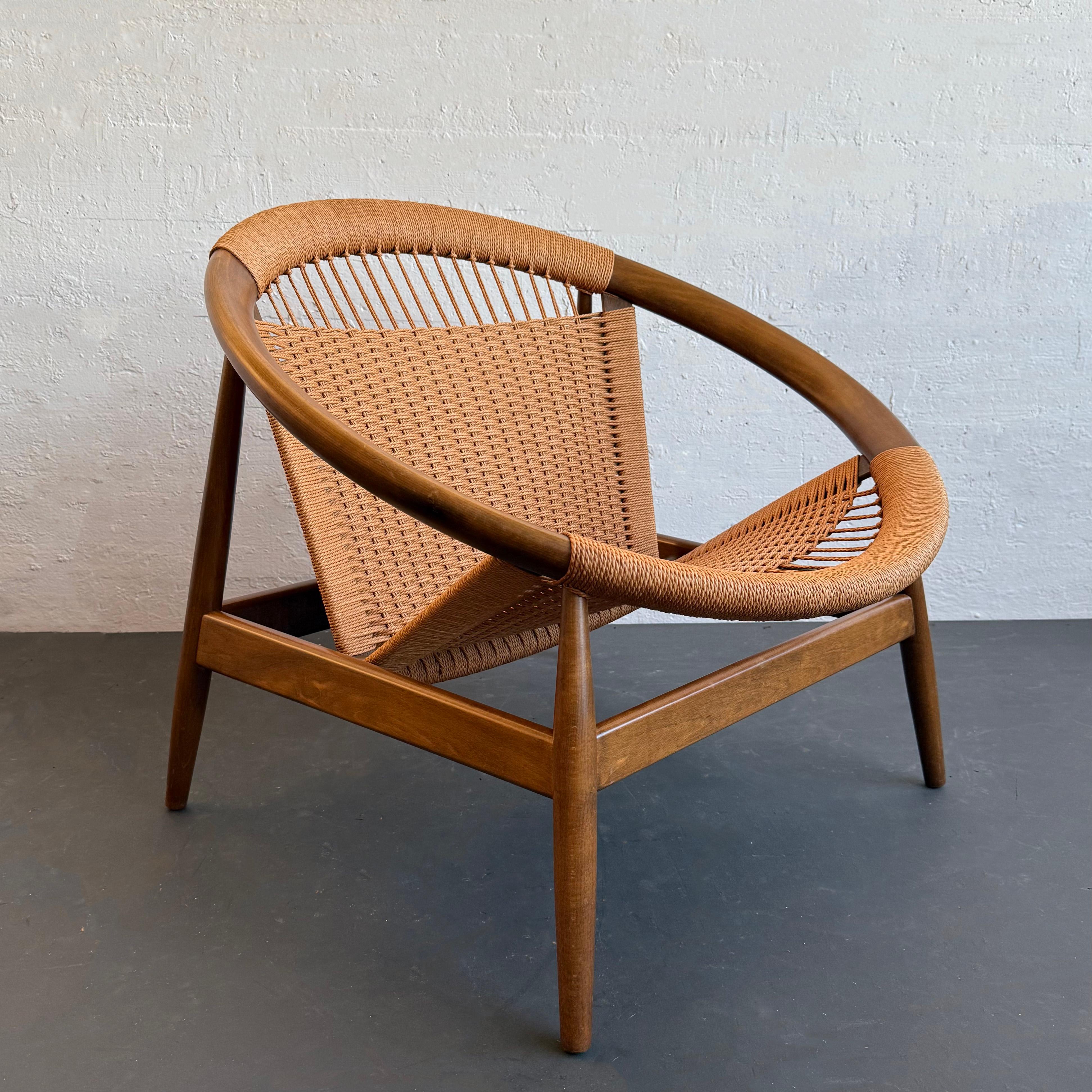 This Scandinavian Modern Ringstol hoop-shaped lounge chair from the 1950s was designed by Danish designer llum Wikkelso for Neils Eilersen. This iconic chair features a circular beech wood frame with woven rope cord seat and back that come together