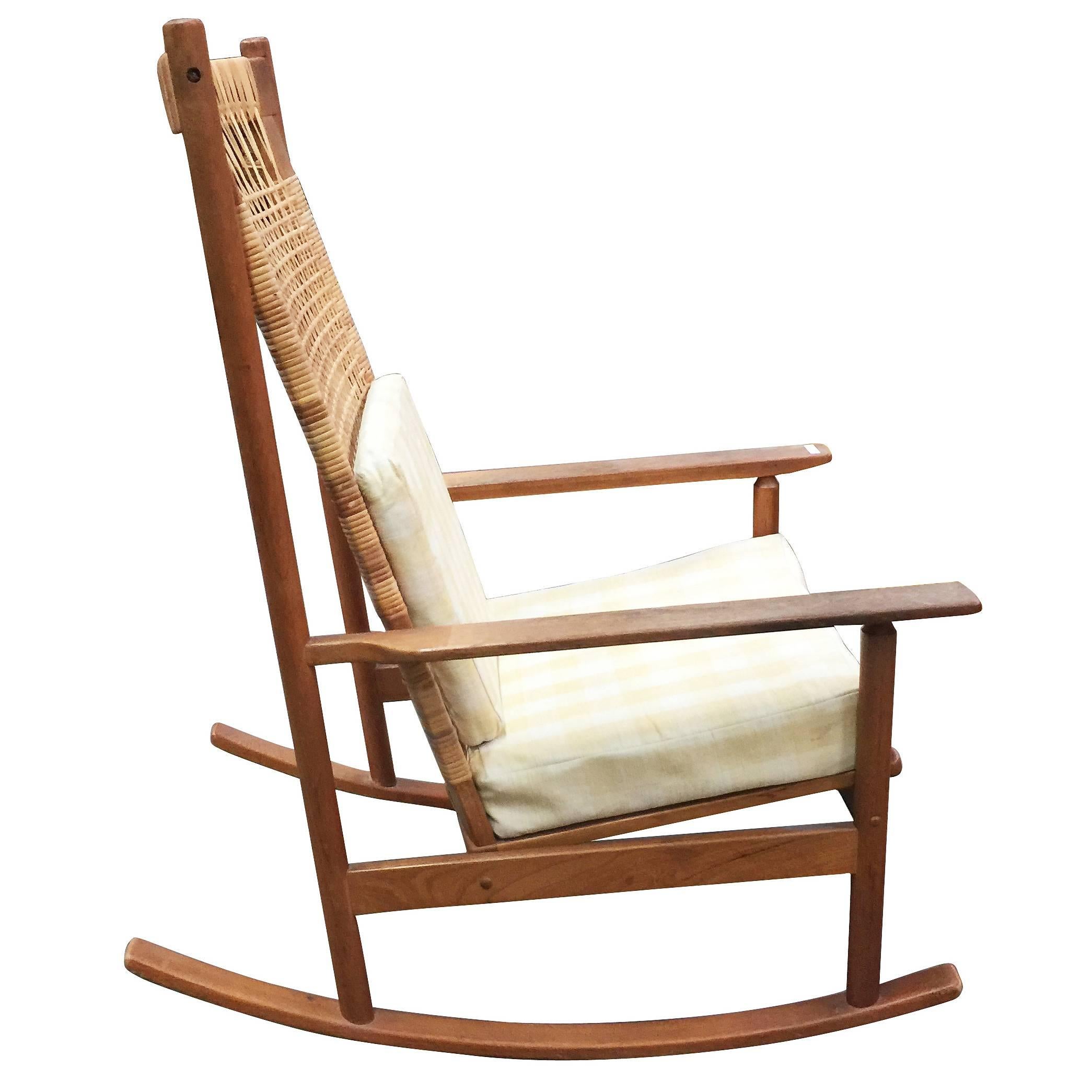 Rare Danish modern rocking chair designed by Hans Olsen for Juul Kristiansen in 1958. The frame is made of teak with a mesh of cane along the back 

Great example of midcentury Danish design. Both the chair and cane back are in a very good