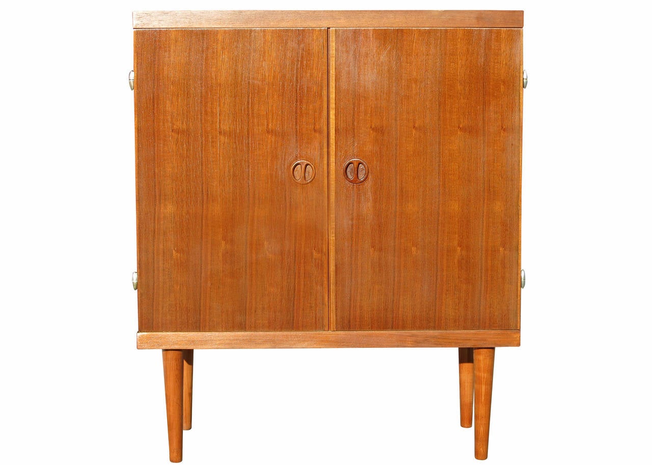 This small Danish style rose stained cabinet has tapered legs, sculpted pig nose pulls and easy swing doors. The cabinet is a great size for a smaller dwelling or for tighter wall space. Ideal for media storage, the interior has one adjustable shelf
