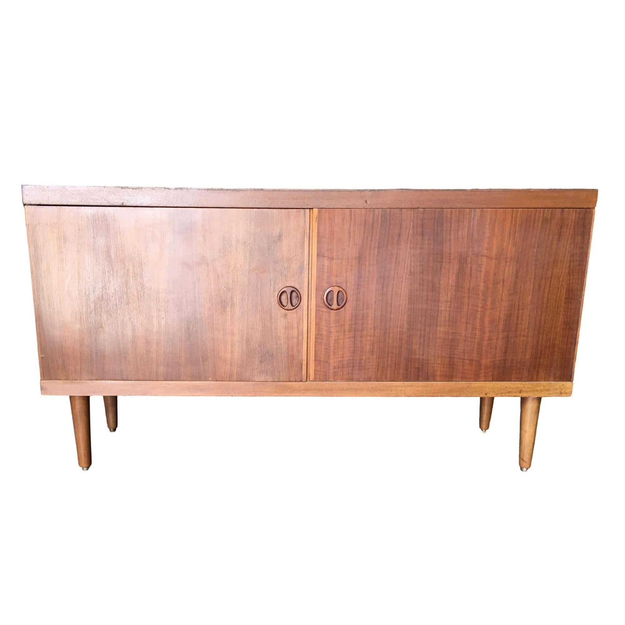 This small Danish style rose stained credenza cabinet with tapered legs, sculpted pig nose pulls and two easy swing doors. It features two large chubby spaces for storage. The cabinet is a great size for a smaller dwelling or for tighter wall space.