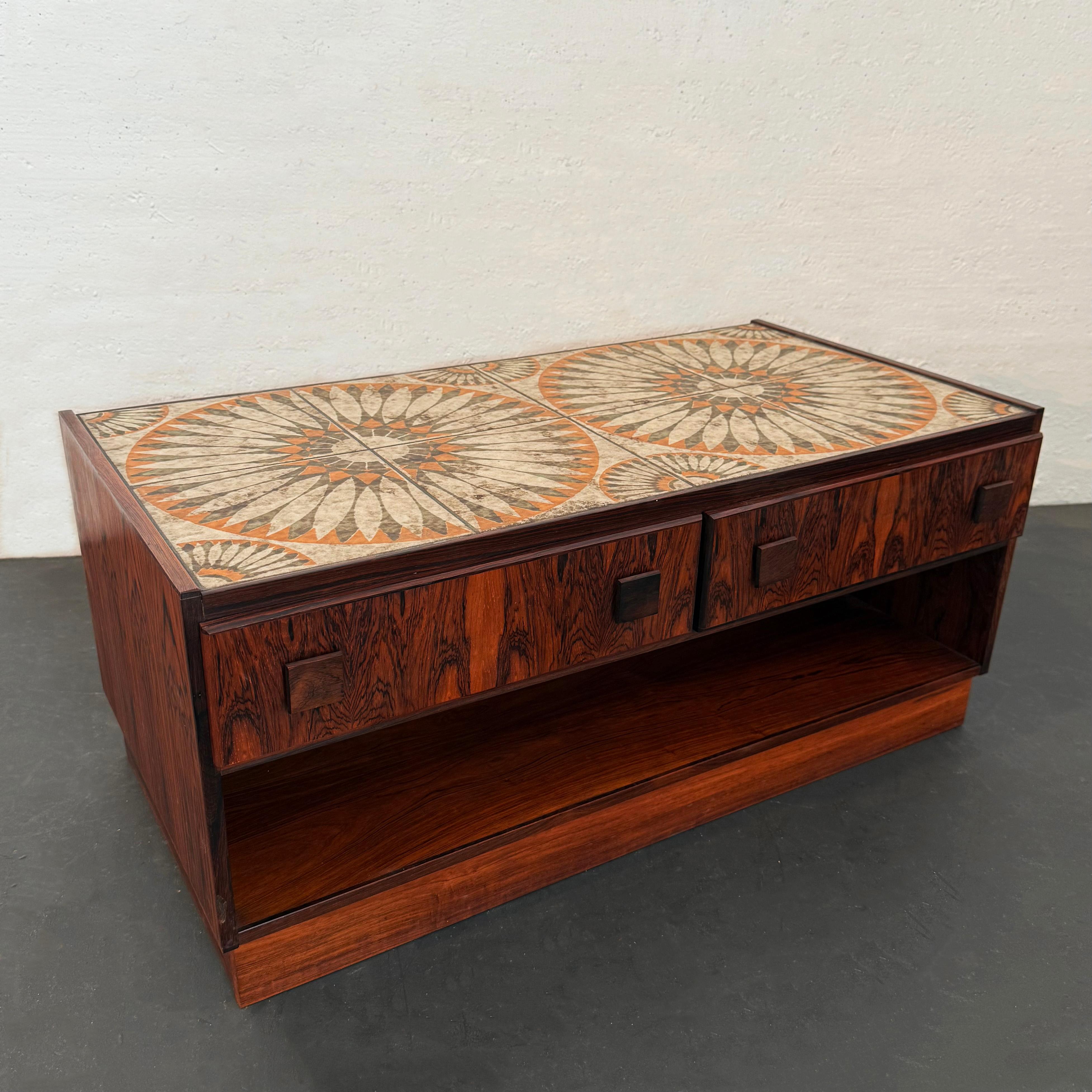 Questo tavolino moderno in legno di palissandro del produttore danese Bornholm Møbelfabrik è un pezzo interessante e versatile. Presenta un corpo in palissandro con una splendida venatura e un piano in ceramica con motivi caleidoscopici. Ci sono due