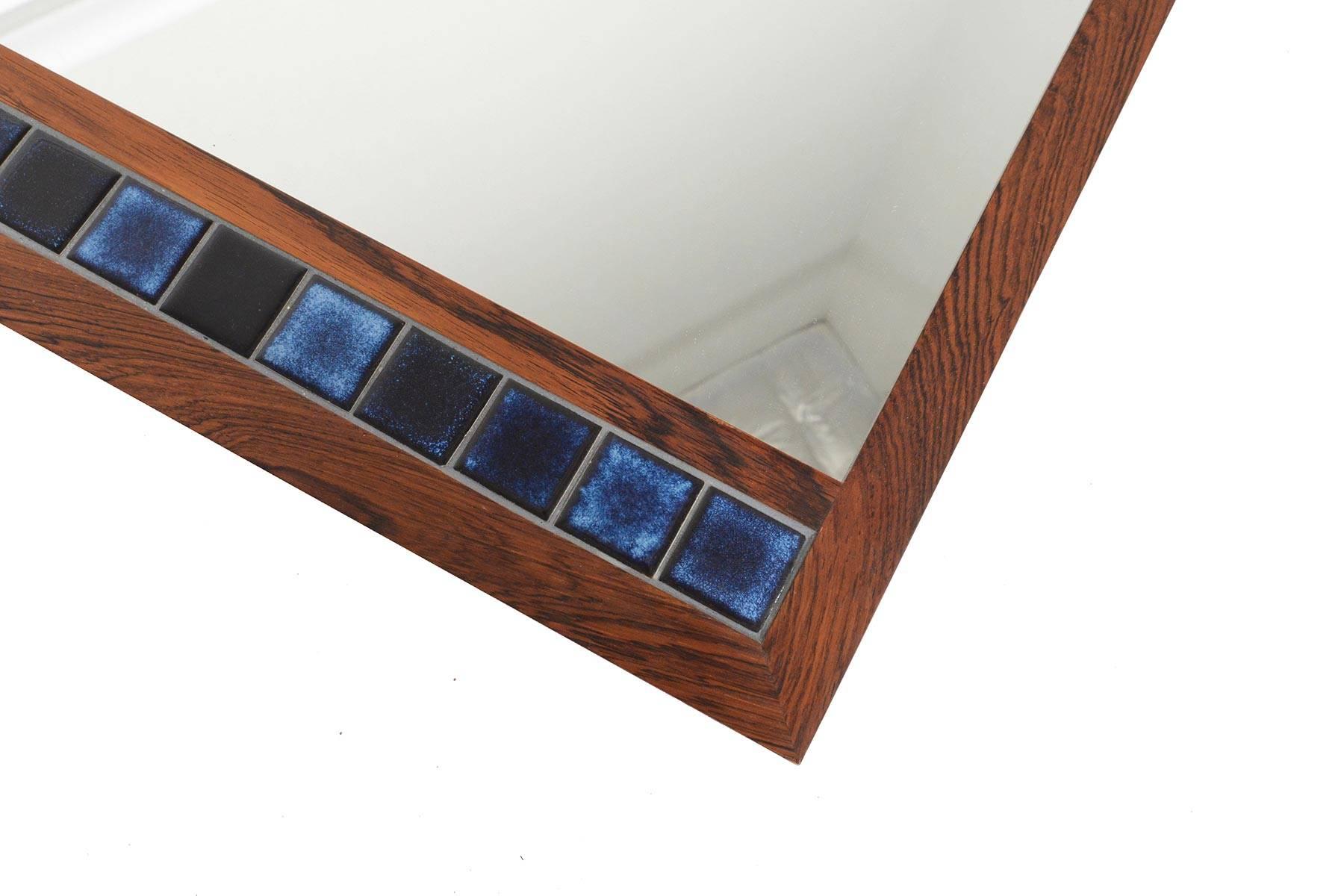 This Danish modern midcentury rosewood framed wall mirror is the perfect accessory for any modern entryway. The rectangular rosewood frame holds blue tiles. In excellent original condition with typical wear for its vintage.

 