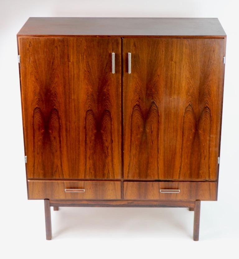 Nice Danish modern freestanding dry bar in rosewood, designed by Axel Christensen, for ACO Møbler. This example features two large doors which swing open to reveal cylindrical bottle holders and a pull out / pull-out black laminate work surface,