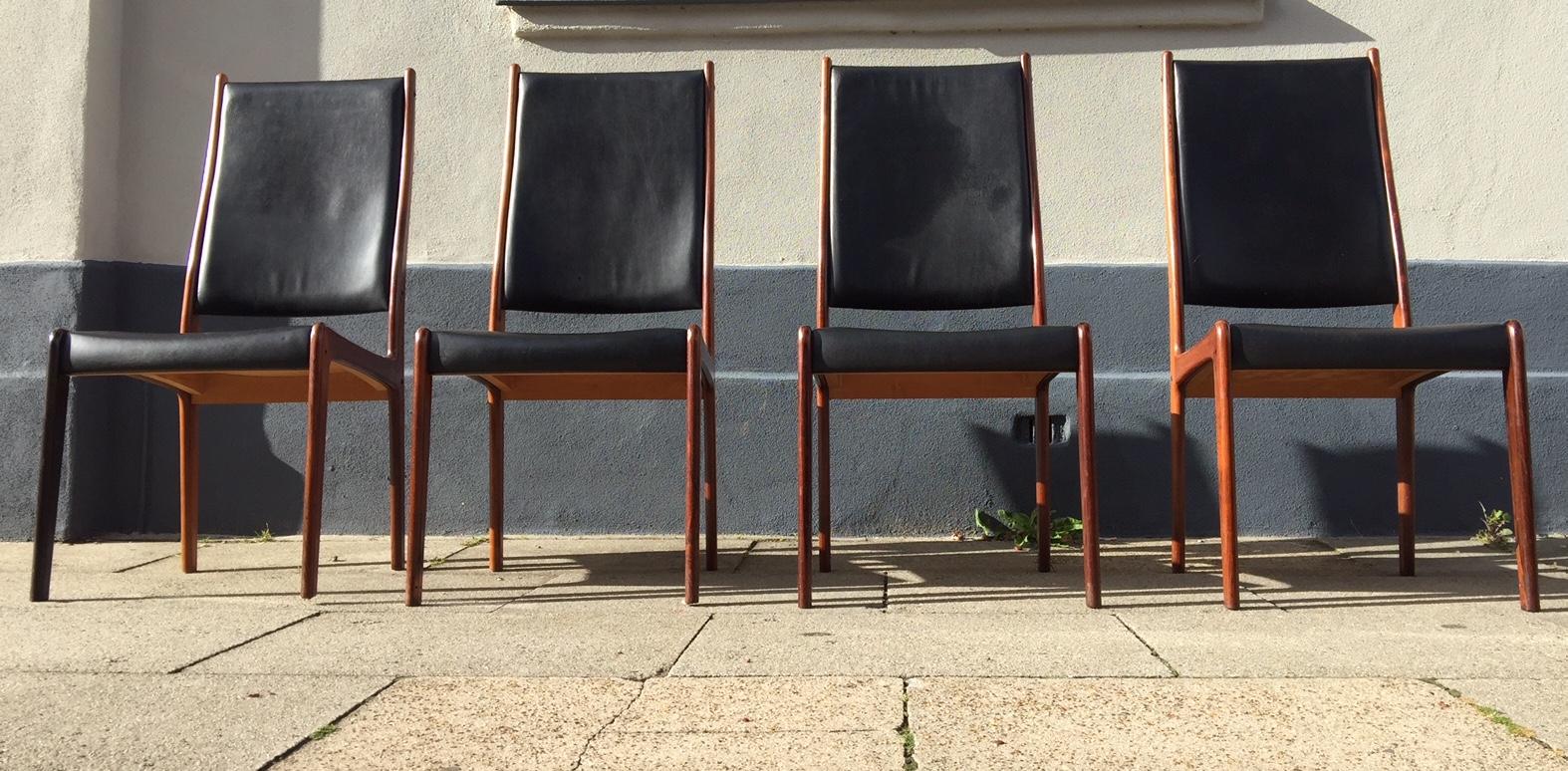 This set of four dining chairs was designed by Johannes Andersen, produced by Mogens Kold, and distributed via Kawolco in Denmark during the 1960s. The chairs are made from rosewood and have the original black leather upholstery.