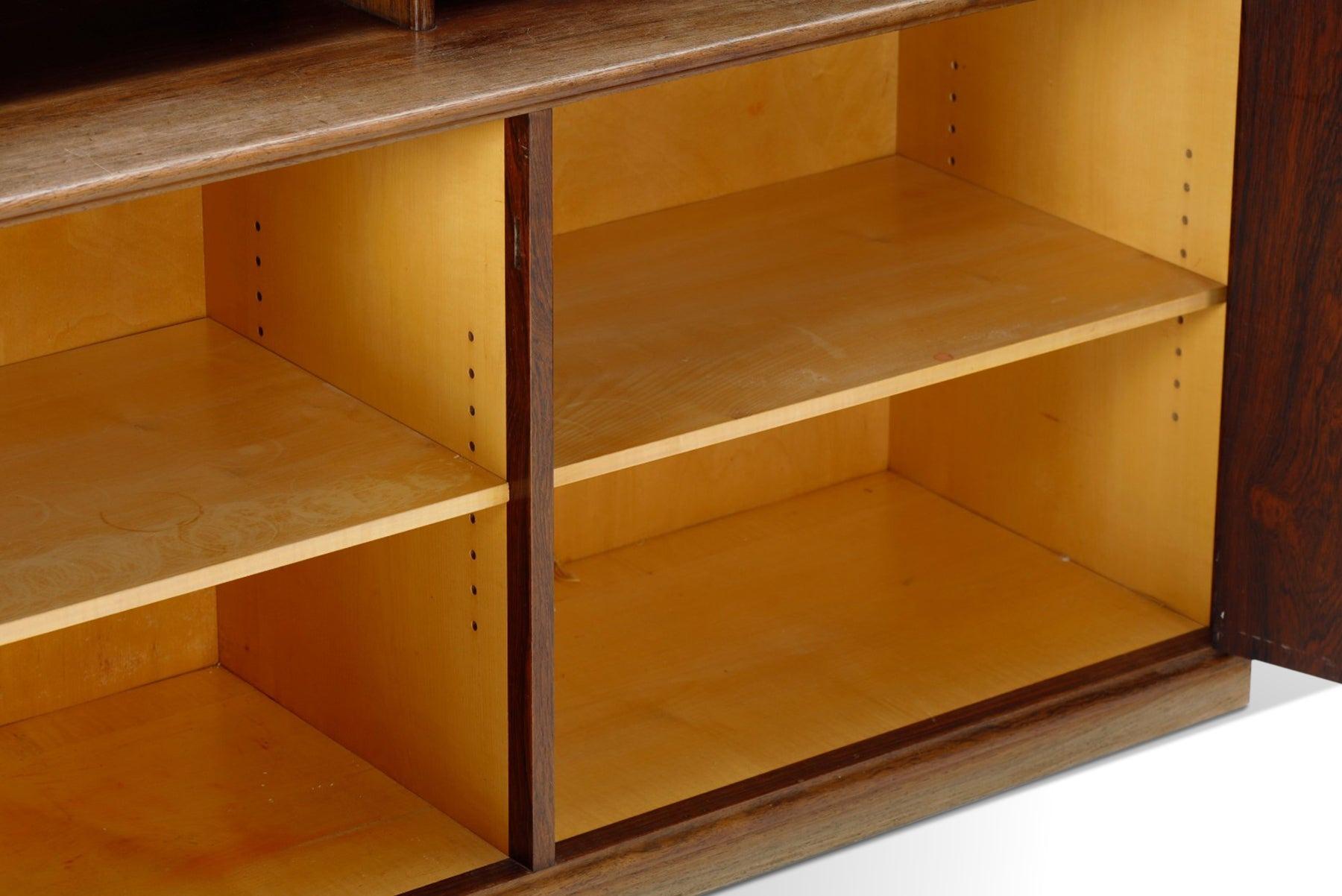 Questa libreria danese moderna di metà secolo in palissandro brasiliano è stata progettata da Frode Holm negli anni '60. Questo imponente pezzo offre una libreria alta a due campate con otto ripiani regolabili. La libreria poggia su una cassa di