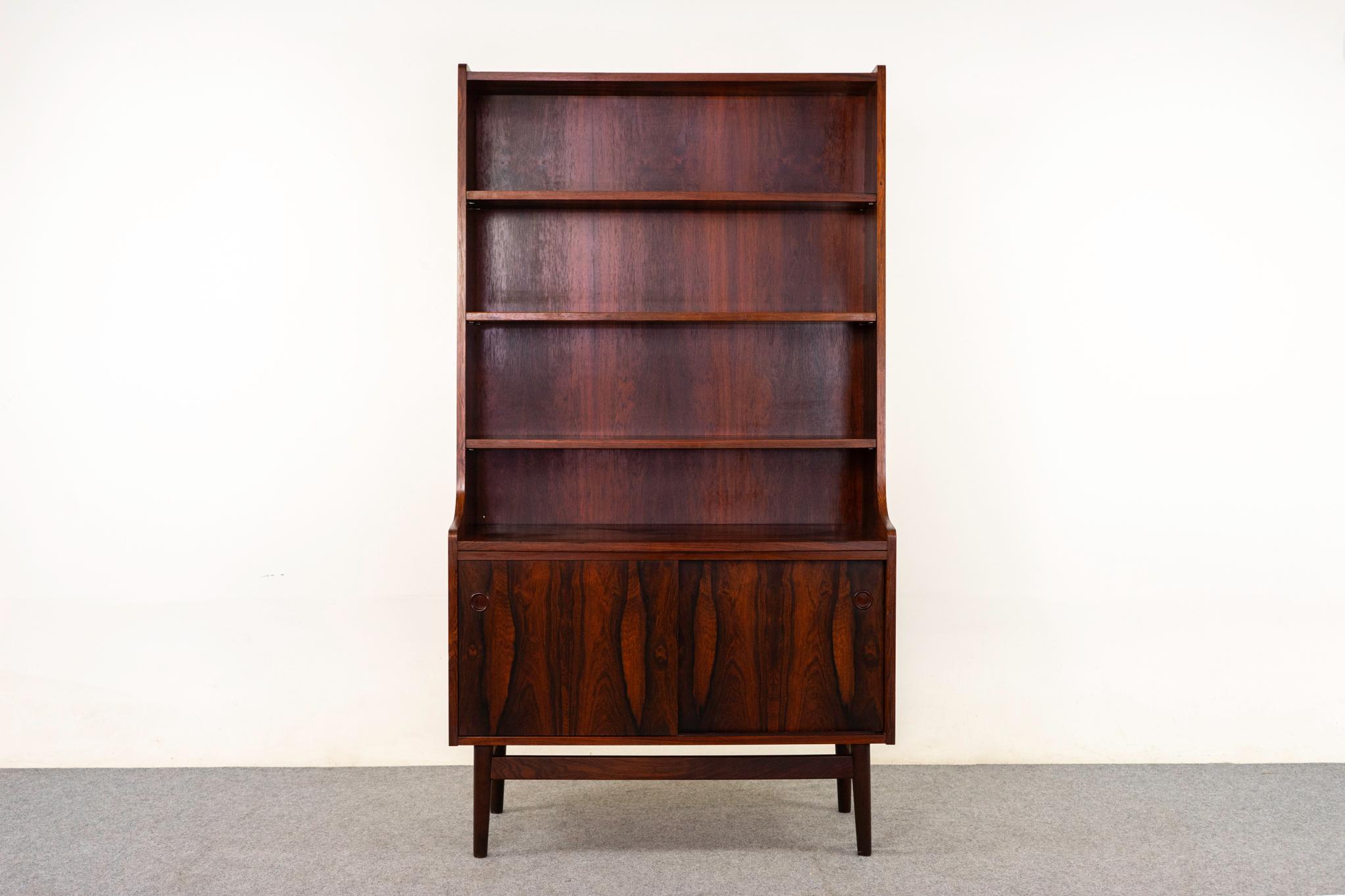 Bücherregal/Schrank aus Palisanderholz, ca. 1960er Jahre. Konisches Bücherregal mit 3 höhenverstellbaren Fachböden. Schiebetürschrank mit verstellbarem Fachboden. Luftiger, schwebender Sockel mit konisch zulaufenden Beinen.

Unrestauriertes Exemplar