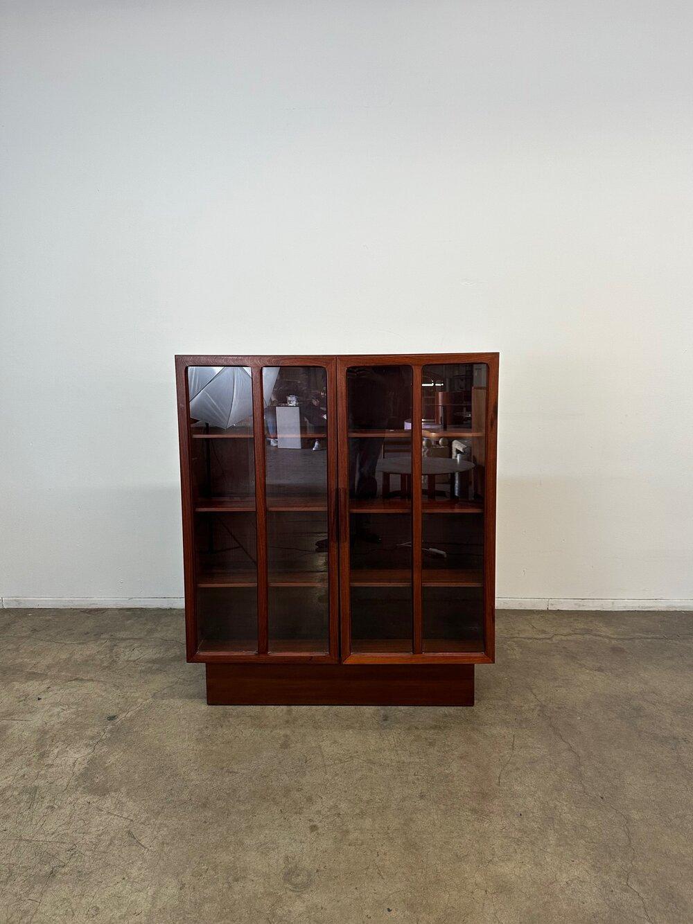 Dimensions: W46 D13 H52

Fully restored rosewood bookcase with glass doors. Item is structurally sound, fully functional and presents well. This item does have heavy glass and wooden doors and item itself should be secured to the wall for added