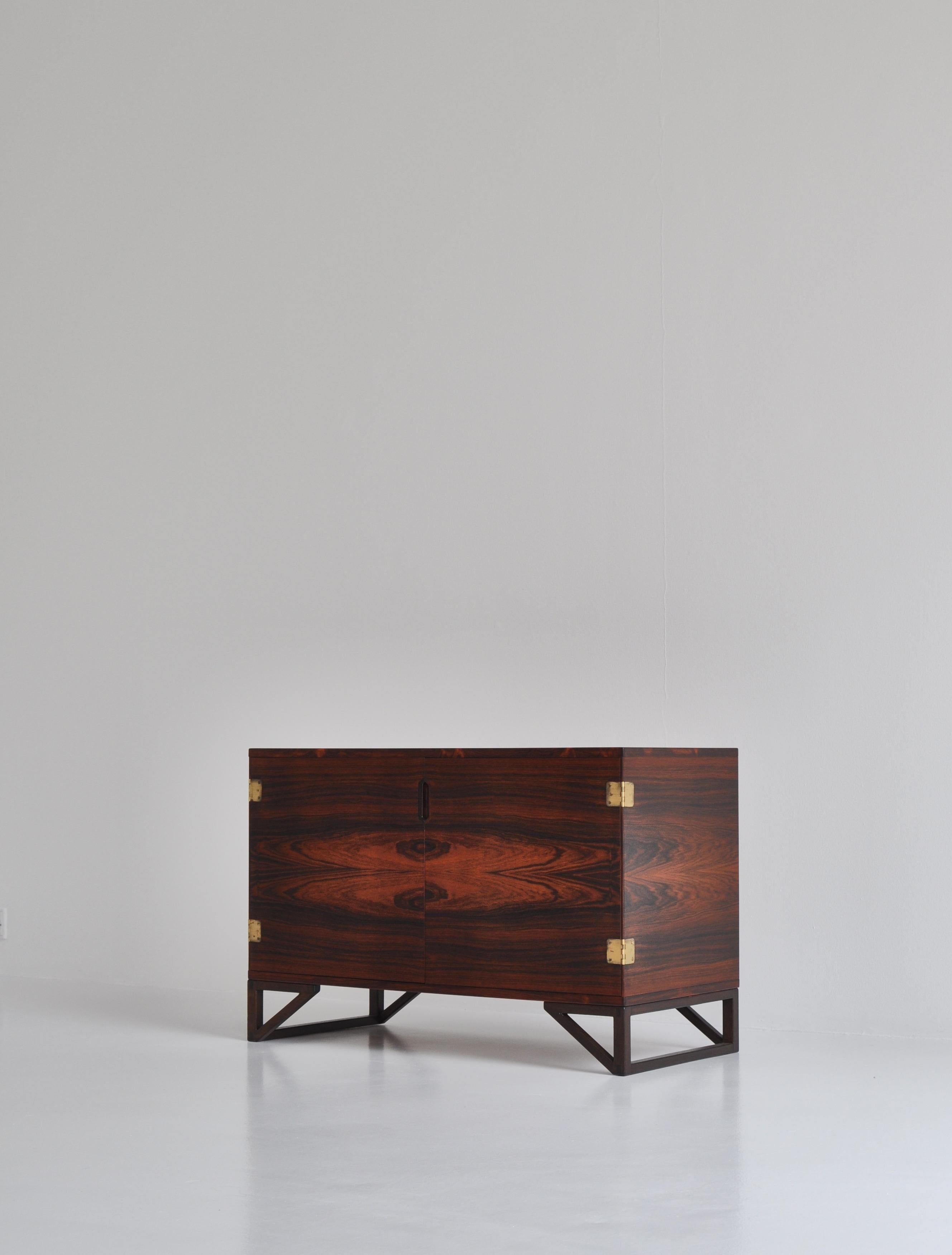 Elegant low sideboard in rosewood by Danish designer Svend Langkilde for Illums Bolighus in the 1960s. The elegant solid teakwood drawers features finger joints and can be pulled out and used as trays. The doors have beautiful hinges in patinated